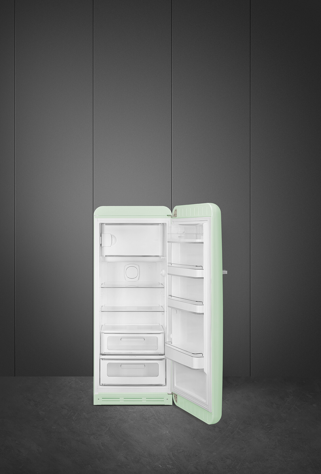 Ein mintgrüner Retro-Kühlschrank mit geöffneter Tür, der weiße Regale und Schubladen zeigt. Er steht vor einem dunkelgrauen Hintergrund.