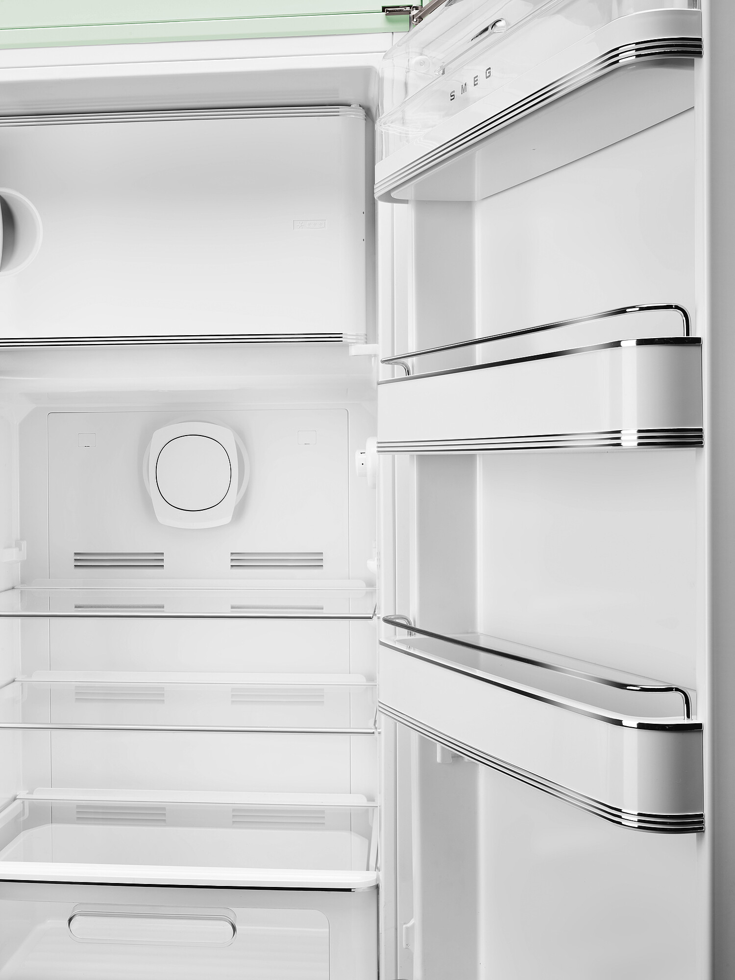 Offener weißer SMEG-Kühlschrank. Innenansicht mit Regalen, Fächern und einem kreisförmigen Element. Chromakzente an der Tür.