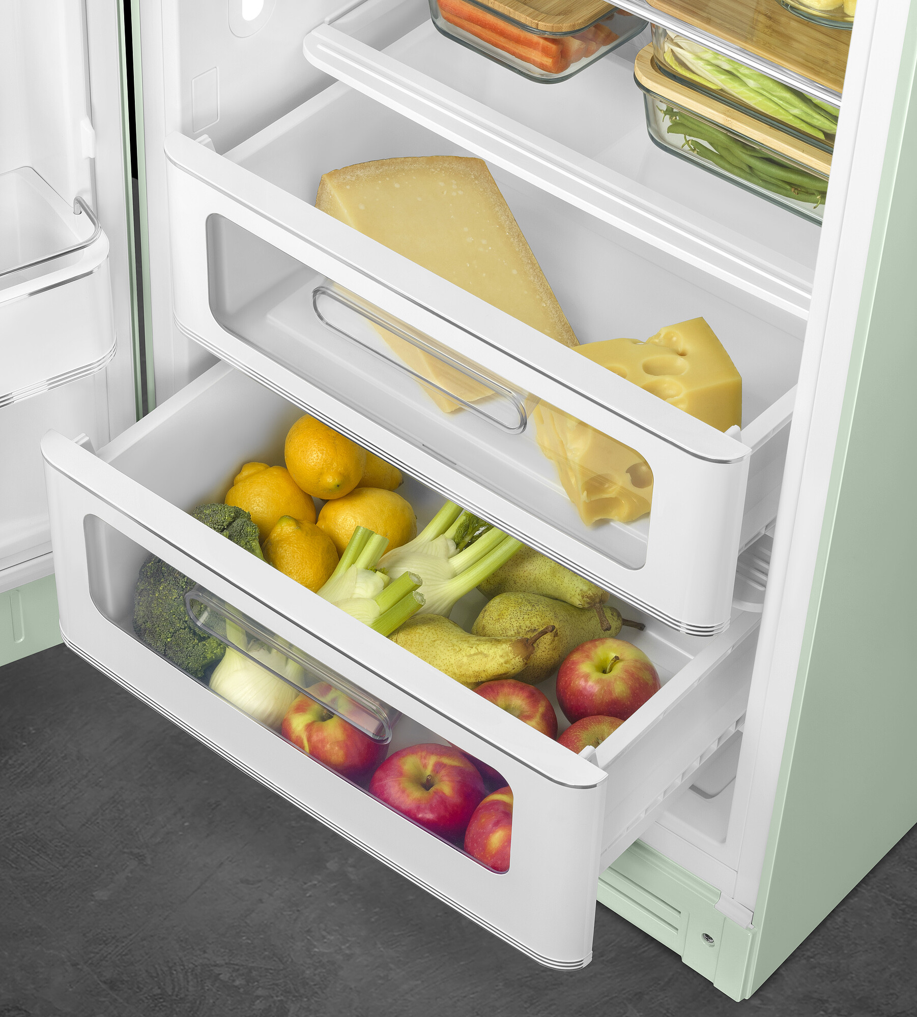 Offener Kühlschrank mit Käse, Zitronen, Äpfeln, Brokkoli und Birnen in den Schubladen. Andere Gegenstände sind auf Regalen sichtbar.