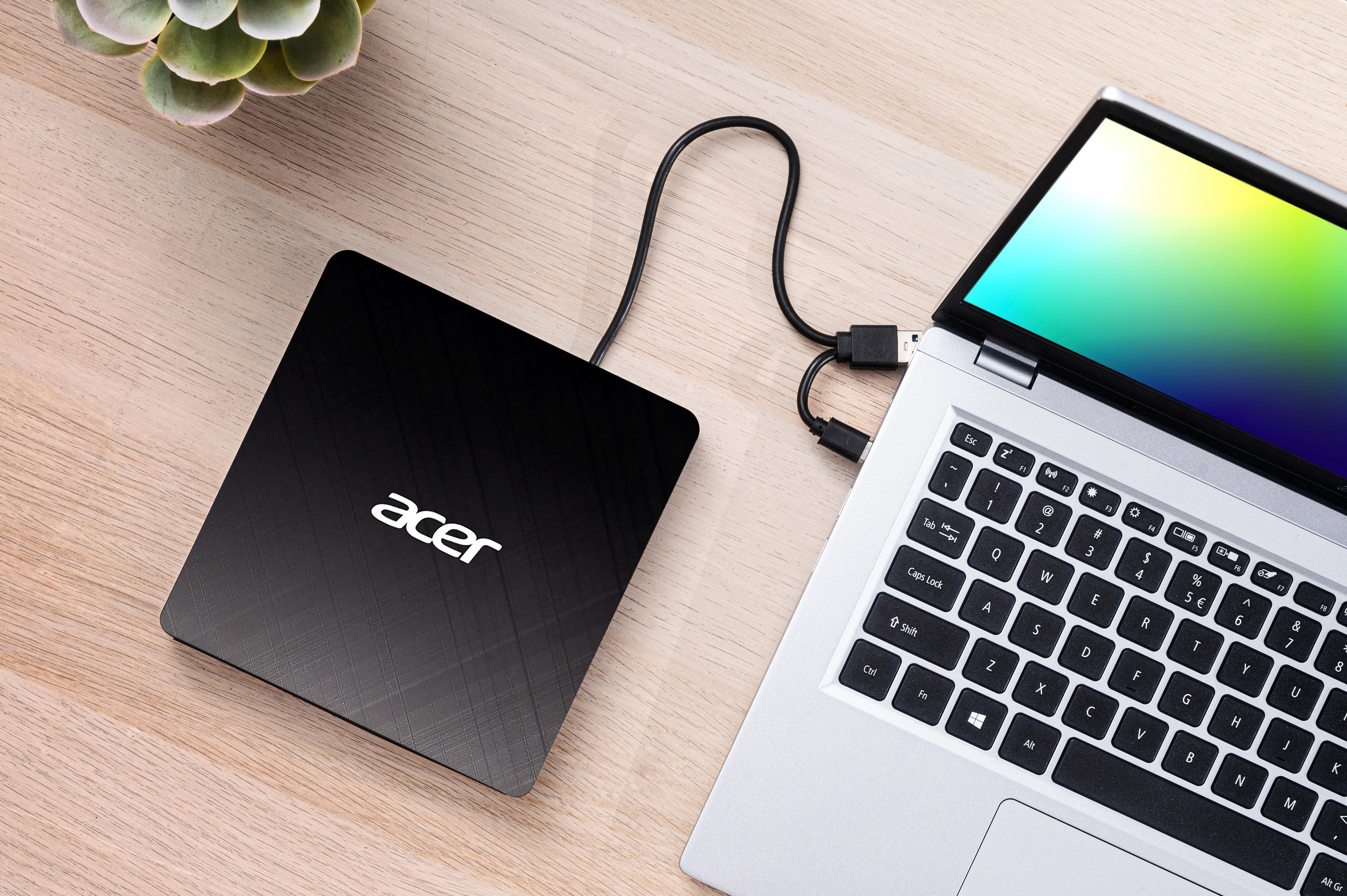 Laptop und externe Festplatte auf einem Holztisch. Der Laptop-Bildschirm zeigt einen bunten Farbverlauf.