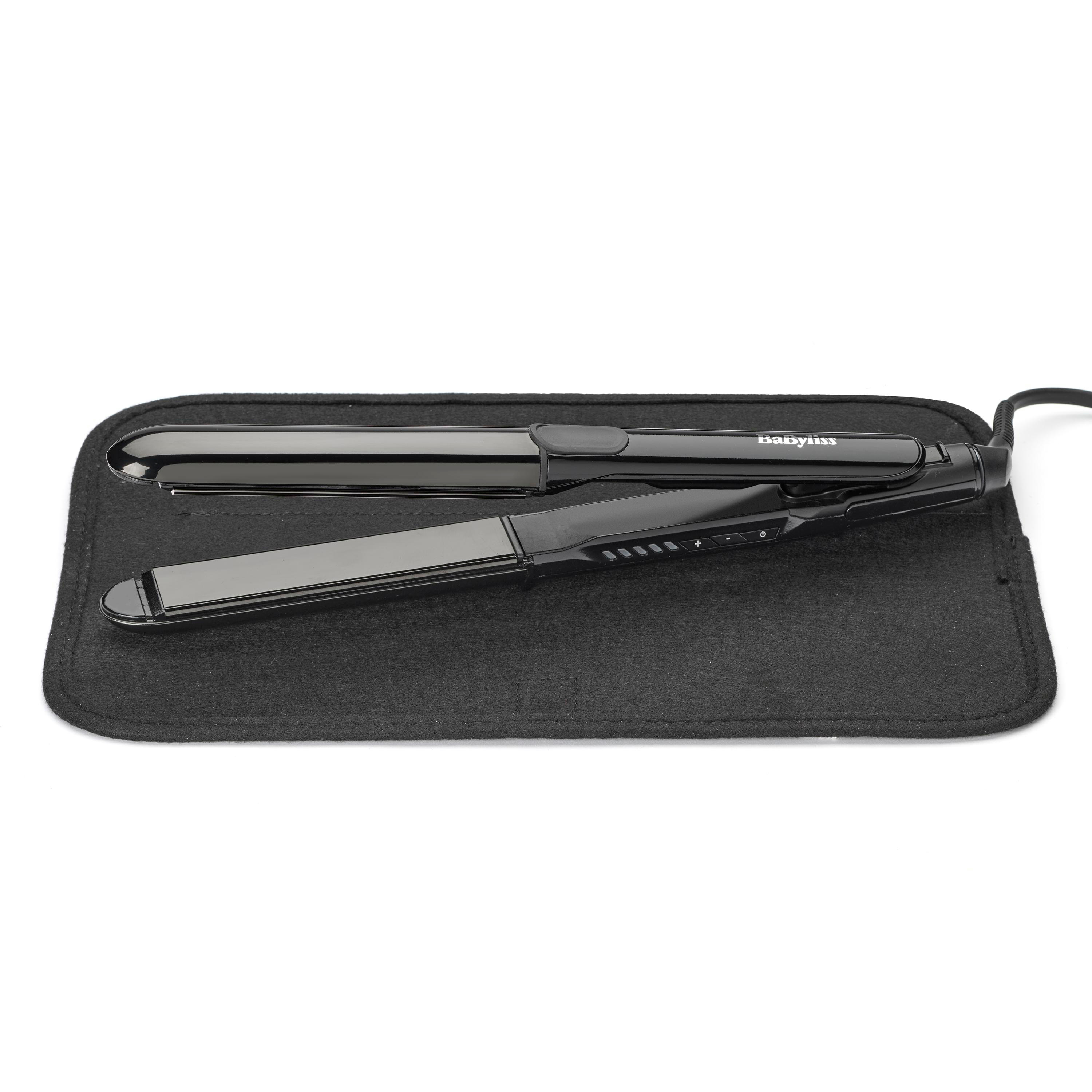 Schwarzes Glätteisen auf einer schwarzen Matte. Das Glätteisen ist mit 'BaByliss' beschriftet. Der Hintergrund ist weiß.