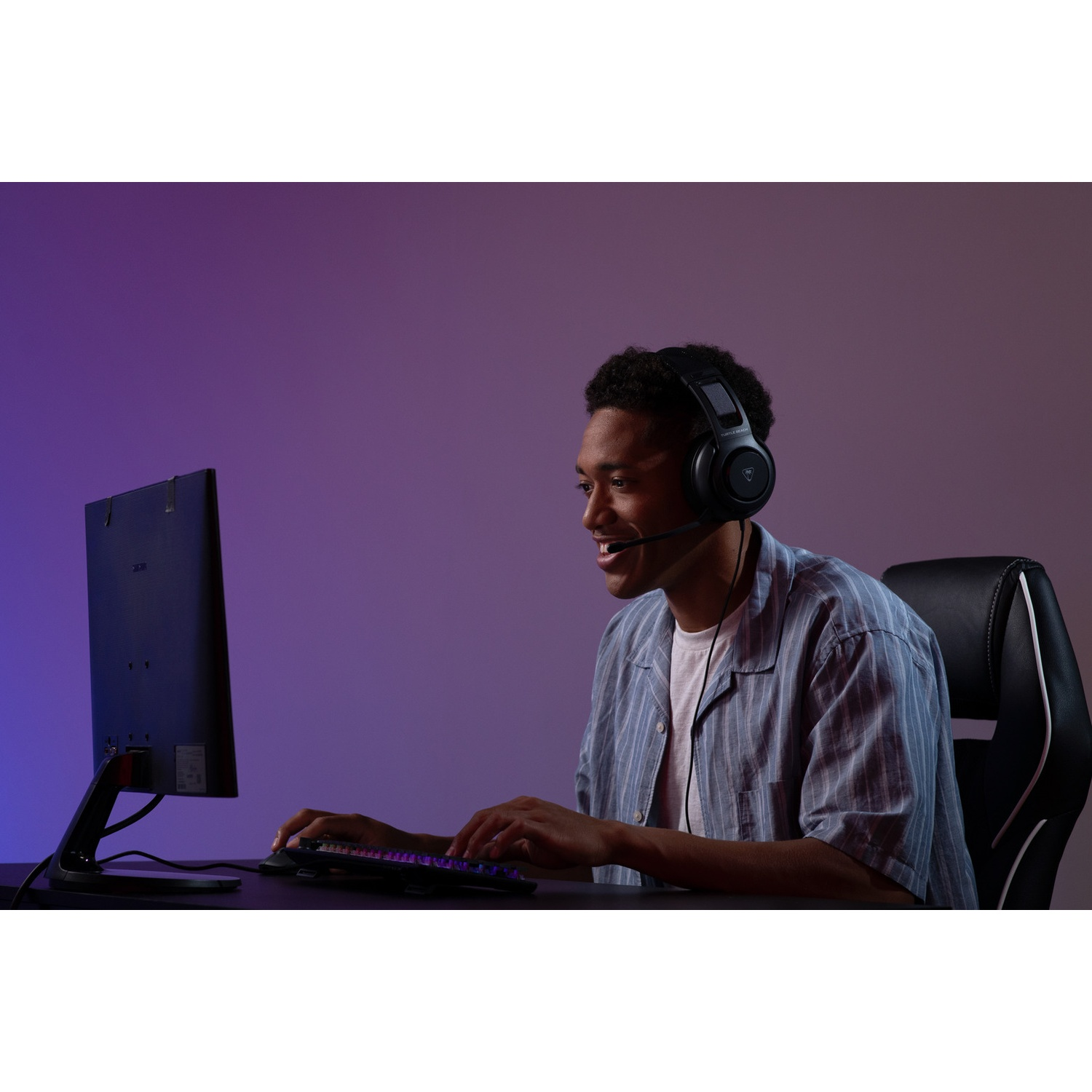 A man wearing a headset is smiling while using a computer. He sits in a gaming chair. The background is a gradient of purple and blue.