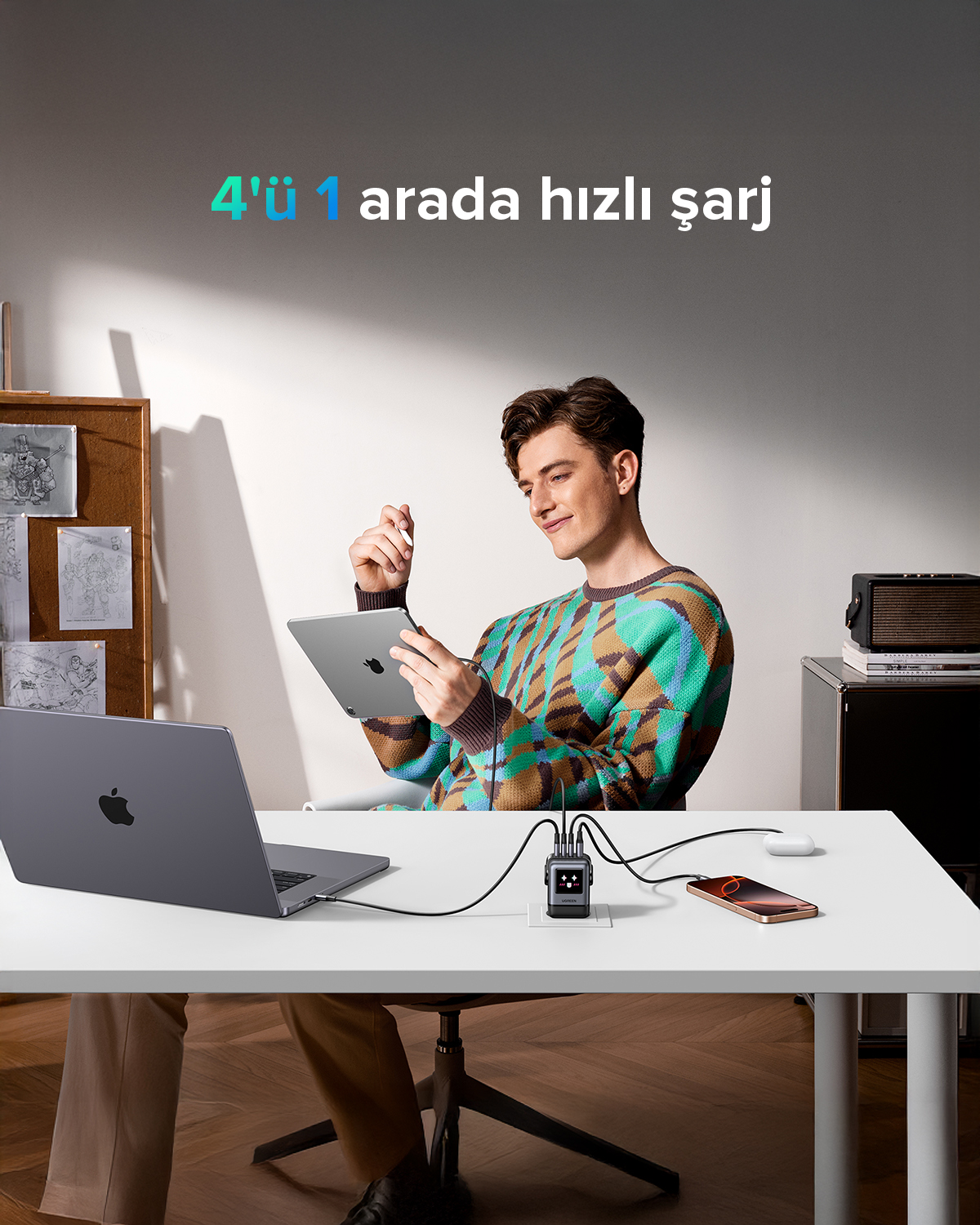 Bir adam, dizüstü bilgisayar, telefon ve şarj cihazıyla bir masada tablet kullanıyor. Metin '4'ü 1 arada hızlı şarj' şeklinde.