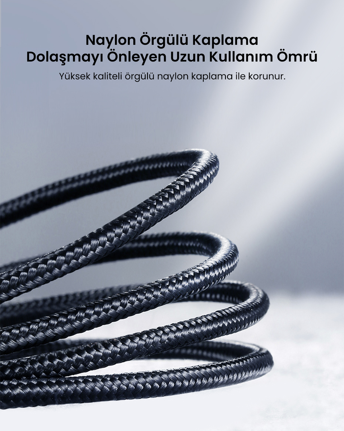Yukarıda Türkçe metin bulunan siyah örgülü bir kablonun yakın çekimi. Arka plan gri ve beyaz bir gradyandır.