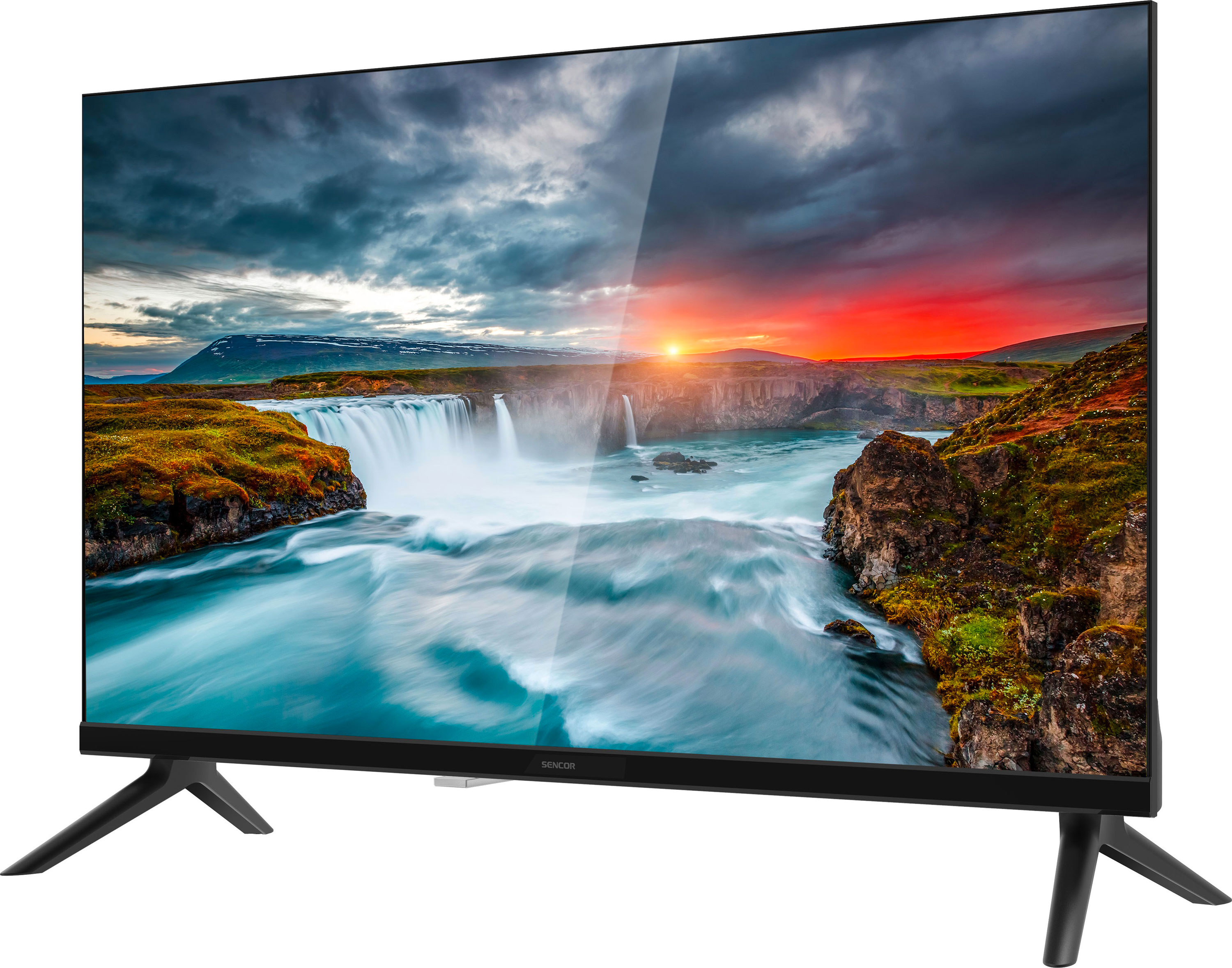 A TV vízesés tájat mutat naplementével. A TV fekete, két lábbal, fehér háttérrel.