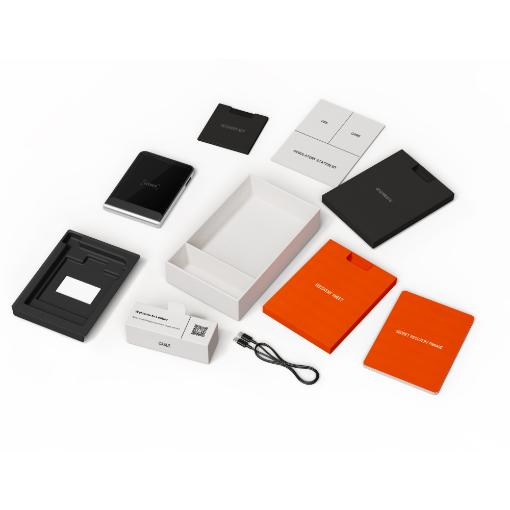 Ledger donanım cüzdan kiti. Ledger cihazı, kutu, kılavuzlar, USB kablosu ve kurtarma sayfaları dahil, beyaz zemin üzerinde.