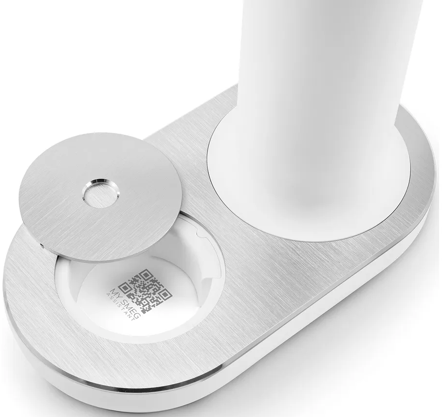 Un dispositivo bianco e argento con un coperchio aperto, che rivela un codice QR. Un elemento cilindrico bianco è sulla destra.