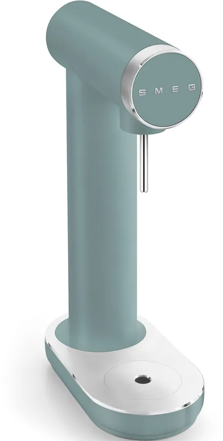 Un distributeur d'eau chaude SMEG de couleur sarcelle. Il a un design arrondi avec une garniture argentée et un bec. La base est blanche avec un trou noir.