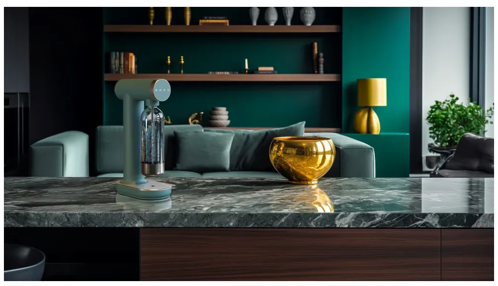 Une cuisine moderne avec un soda maker, un bol doré et un canapé vert. Le comptoir en marbre reflète les objets. L'arrière-plan est un mur vert foncé.