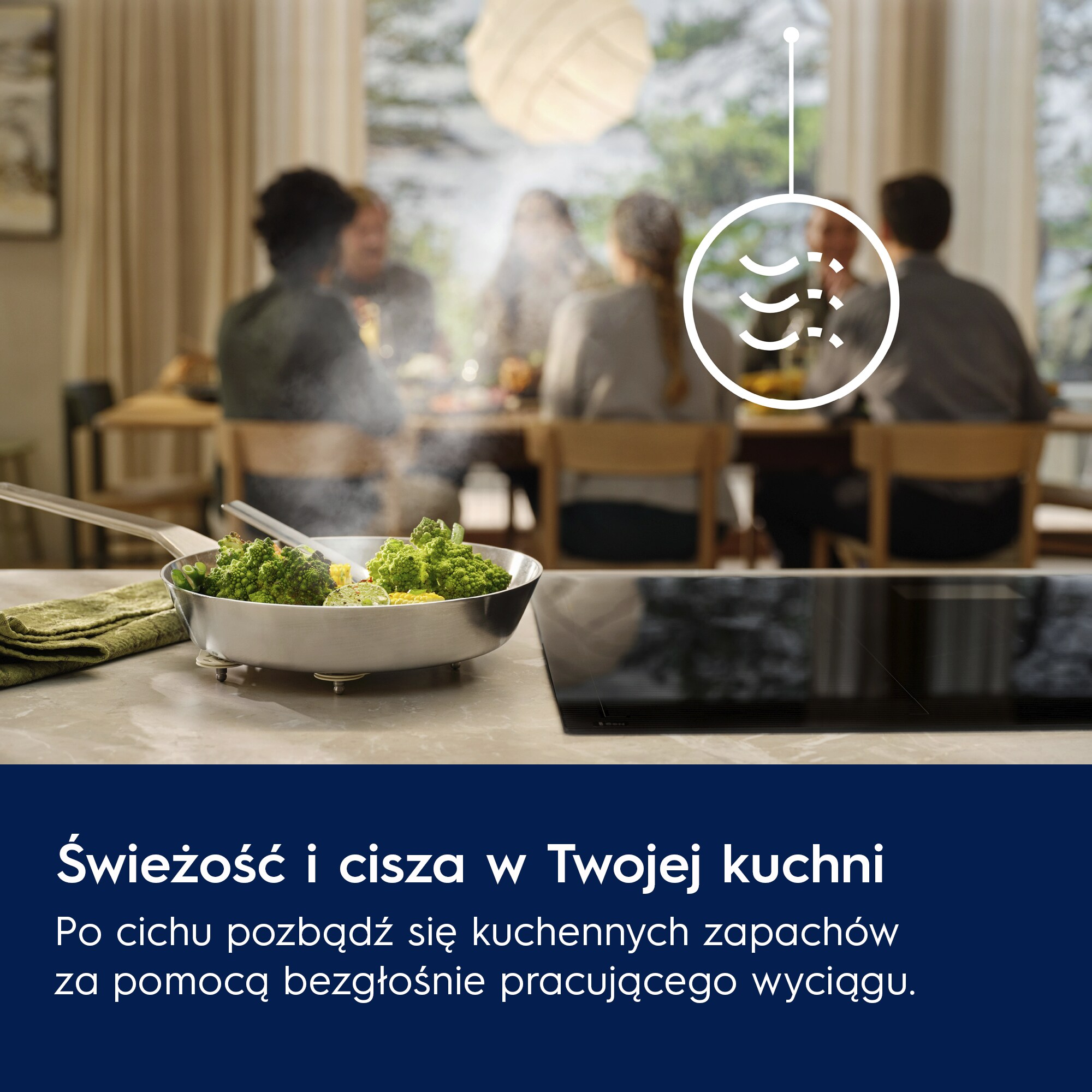 Patelnia z warzywami paruje na blacie. Ludzie jedzą w rozmytym tle. Ikona okapu znajduje się nad nią.