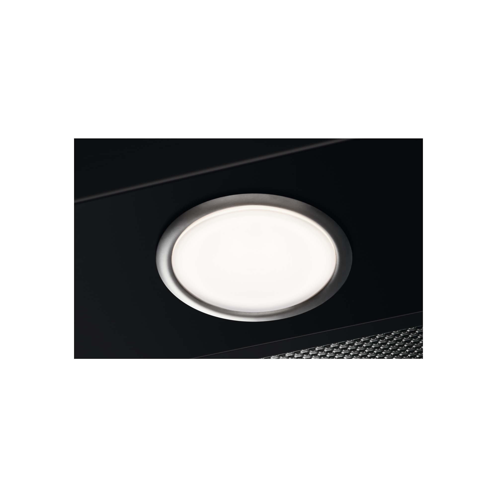 Zbliżenie jasnej, okrągłej oprawy oświetleniowej ze srebrną obwódką na czarnym tle.