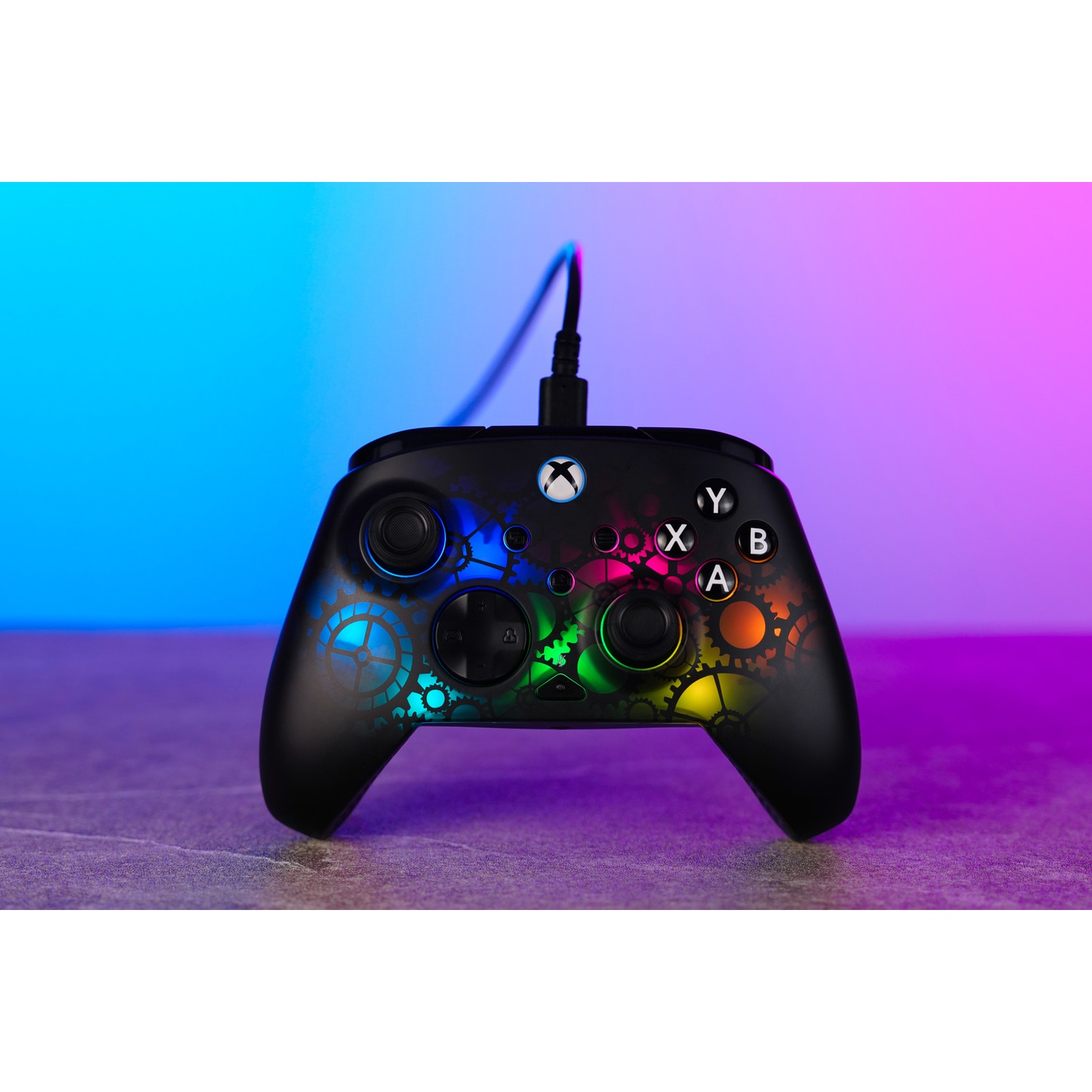 Black Xbox controller with colorful gear design, buttons, and a connected cable, set against a blue and purple gradient.