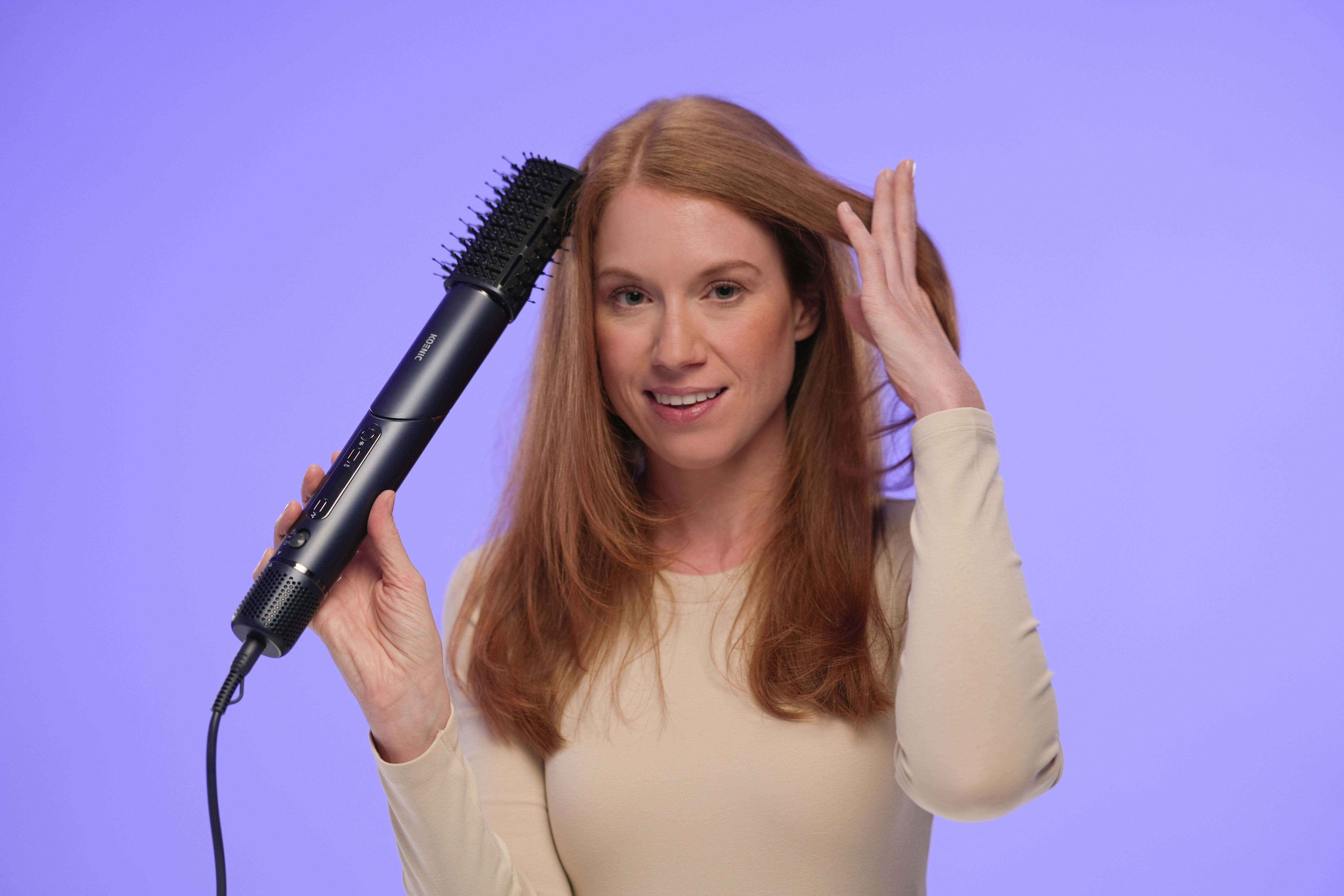 Frau benutzt eine Haarbürste. Sie hat rotes Haar und trägt ein beiges Hemd, das sie nahe ihrem Haar hält.