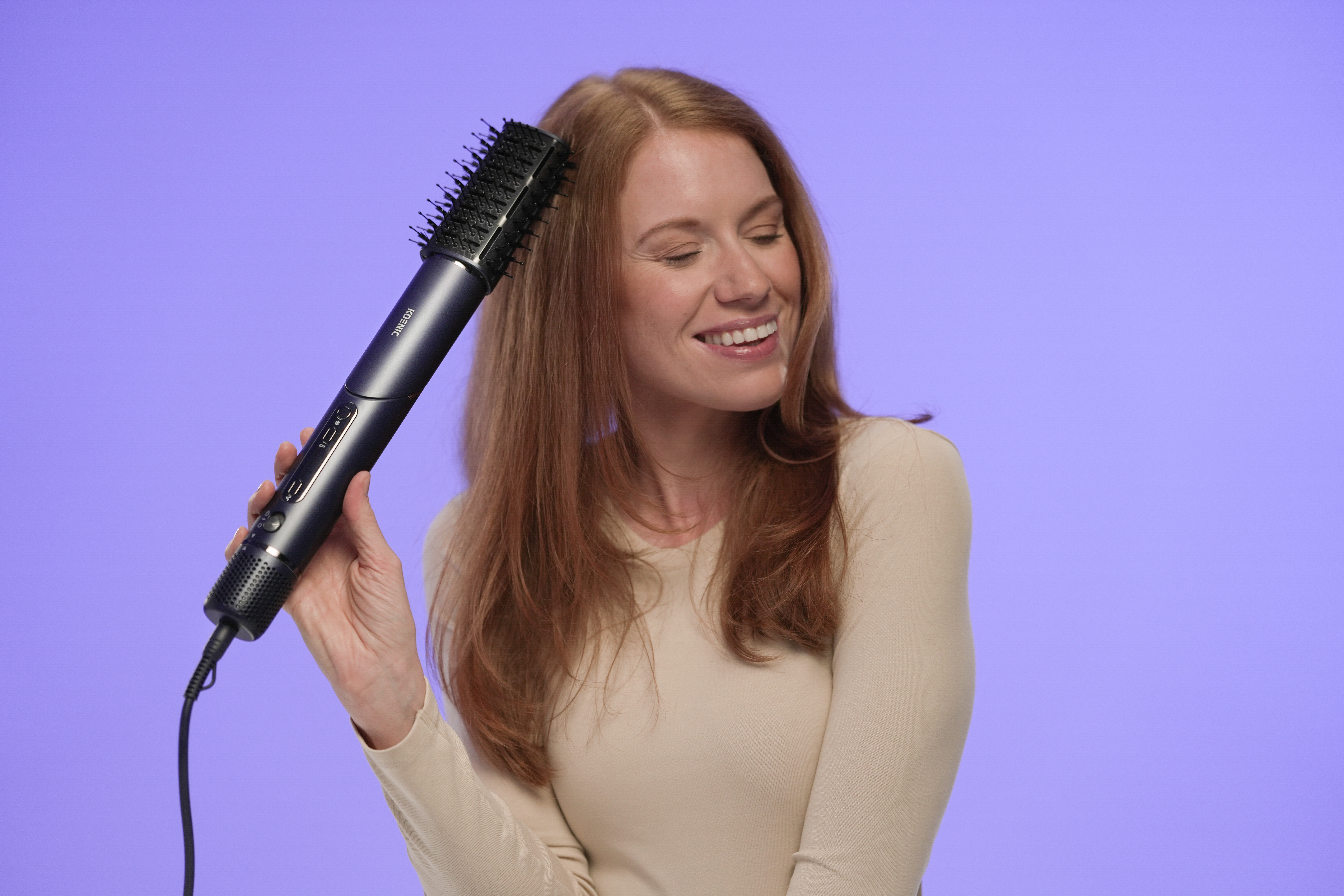 Eine Frau mit roten Haaren benutzt eine Haarbürste. Sie lächelt. Der Hintergrund ist einfarbig lila.