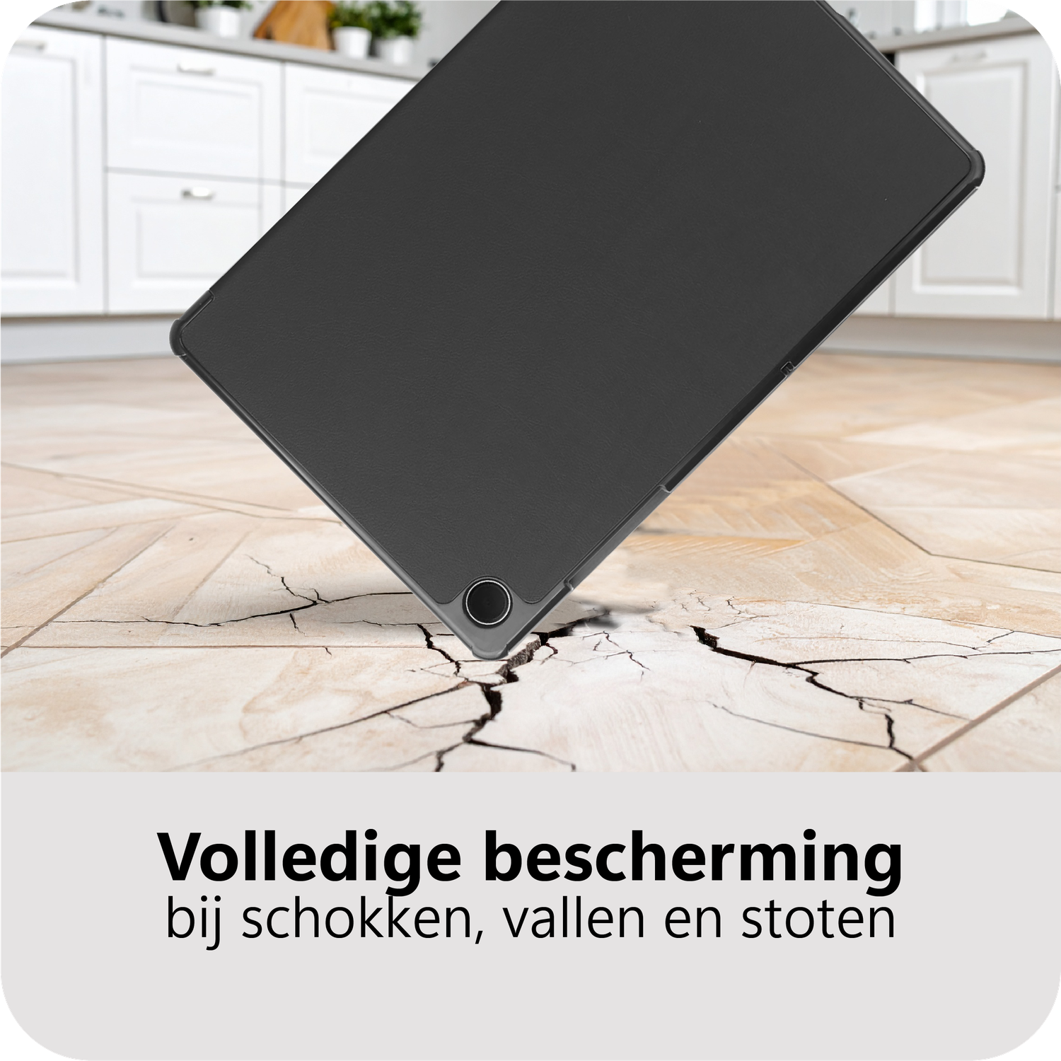 Een zwarte tablet valt op een betegelde vloer en veroorzaakt scheuren. Keukenkasten op de achtergrond.