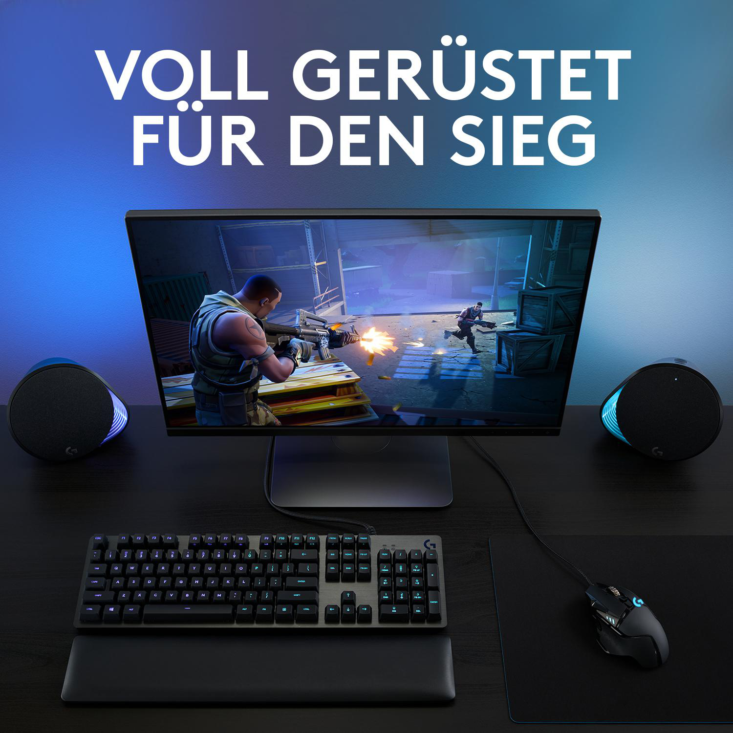 Ein Gaming-Setup mit einem Monitor, der eine Spielszene zeigt, einer Tastatur, Maus und Lautsprechern auf einem dunklen Schreibtisch.