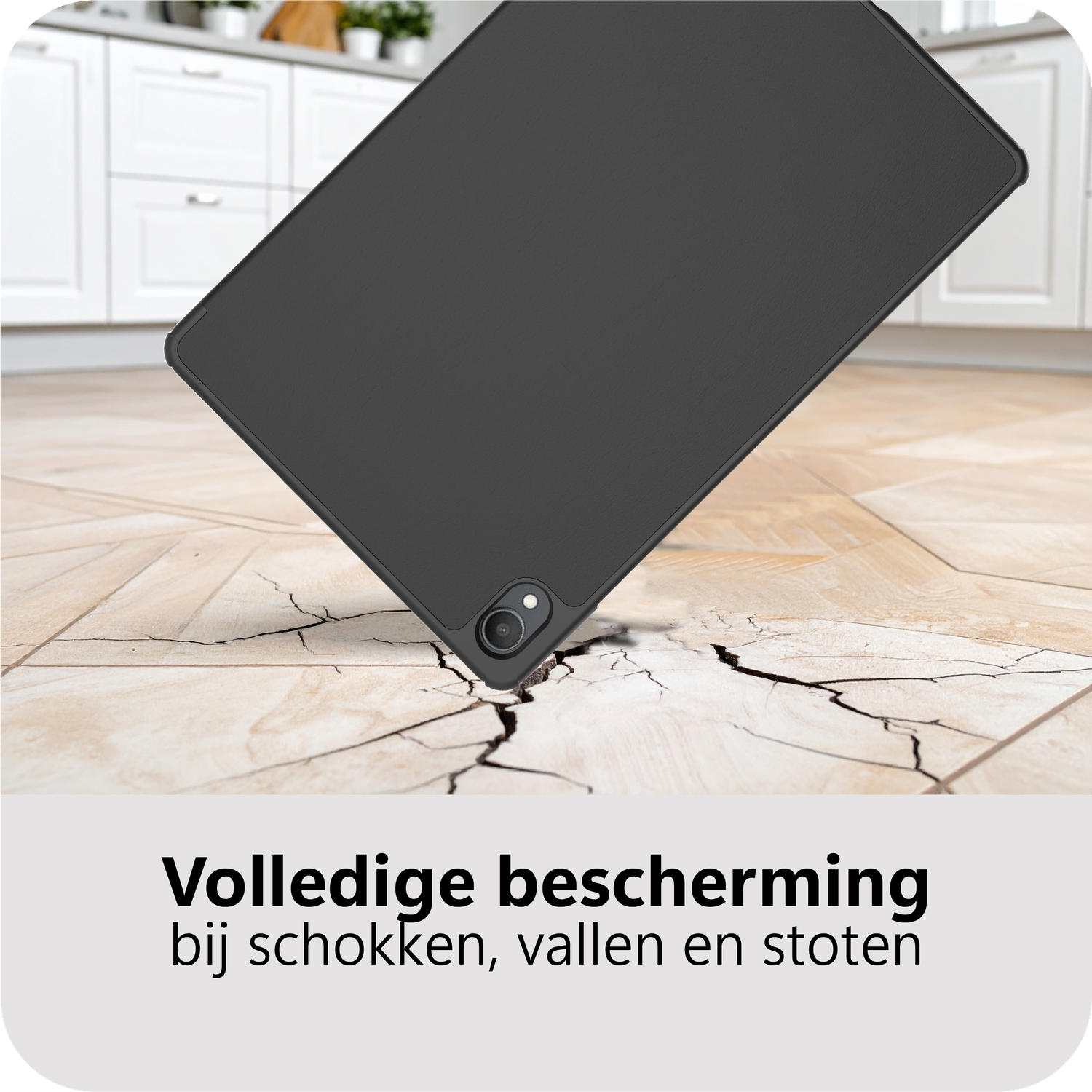Een zwarte tablet valt op een gebarsten houten vloer. Een keuken met witte kasten staat op de achtergrond. Nederlandse tekst onderaan.