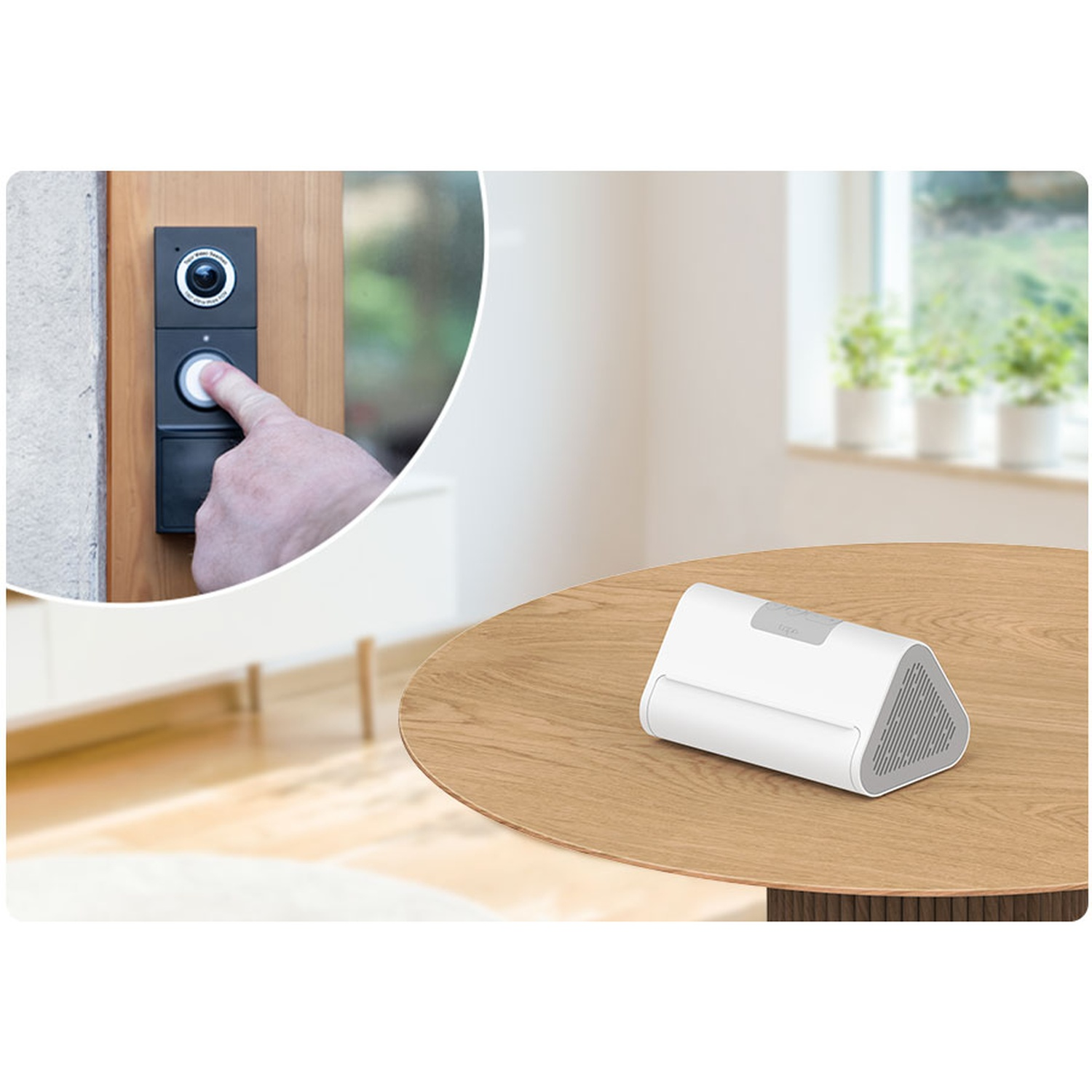 A hand presses a doorbell. A white device sits on a wooden table. A window with plants in pots is in the background.