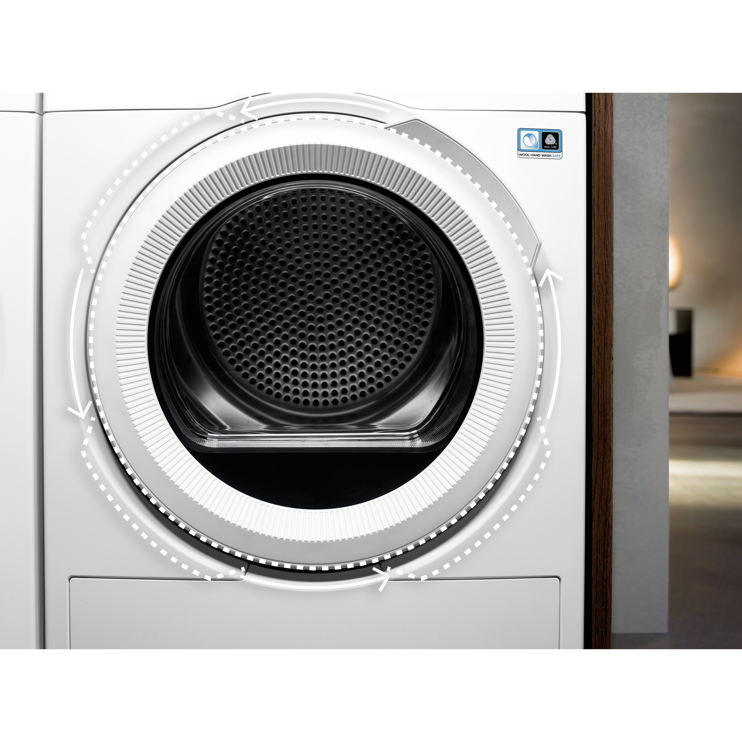 A white dryer with a black interior. A circular design with arrows shows the cycle. A wool care logo is present.