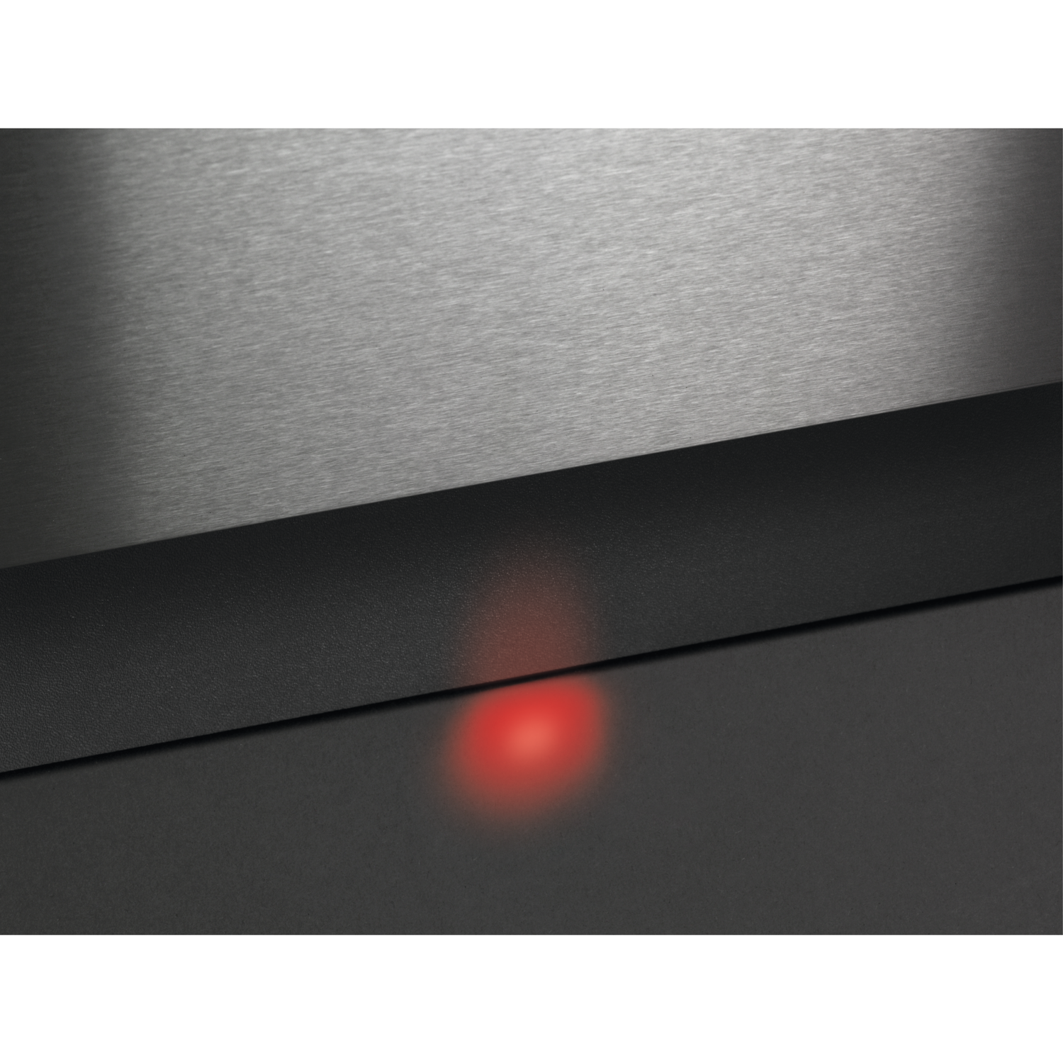 Close-up van een geborsteld metalen oppervlak met een zwarte, getextureerde band. Een rood licht gloeit van onder de band.