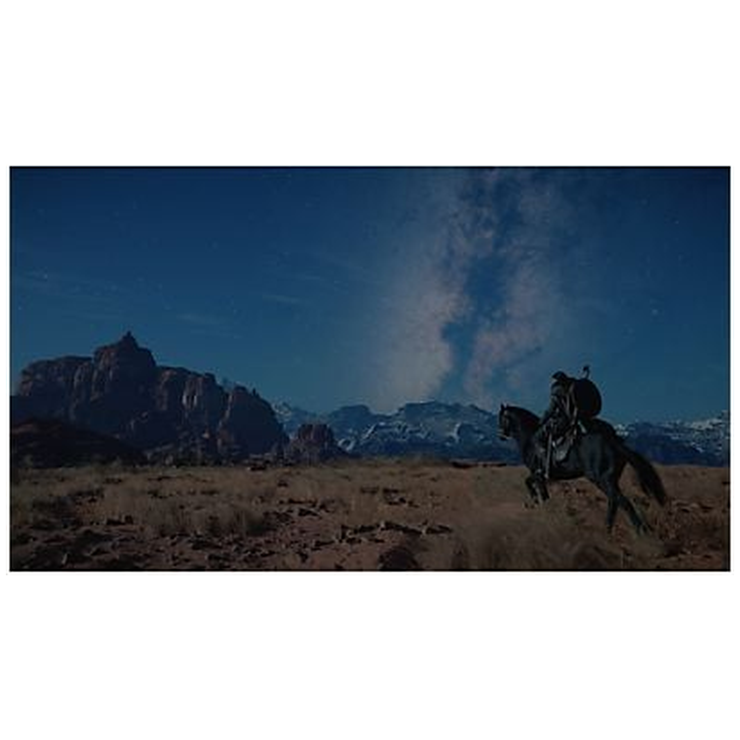 A rider on a black horse jumps across a desert landscape under a starry night sky. Mountains are in the background.