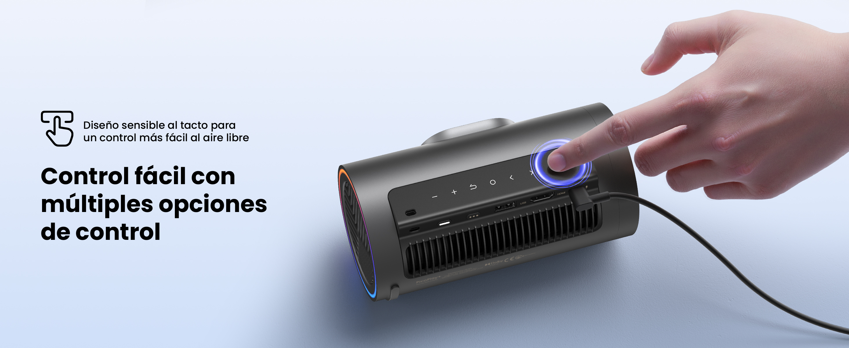 Una mano toca un botón en un proyector negro. El proyector tiene múltiples opciones de control. El fondo es blanco.