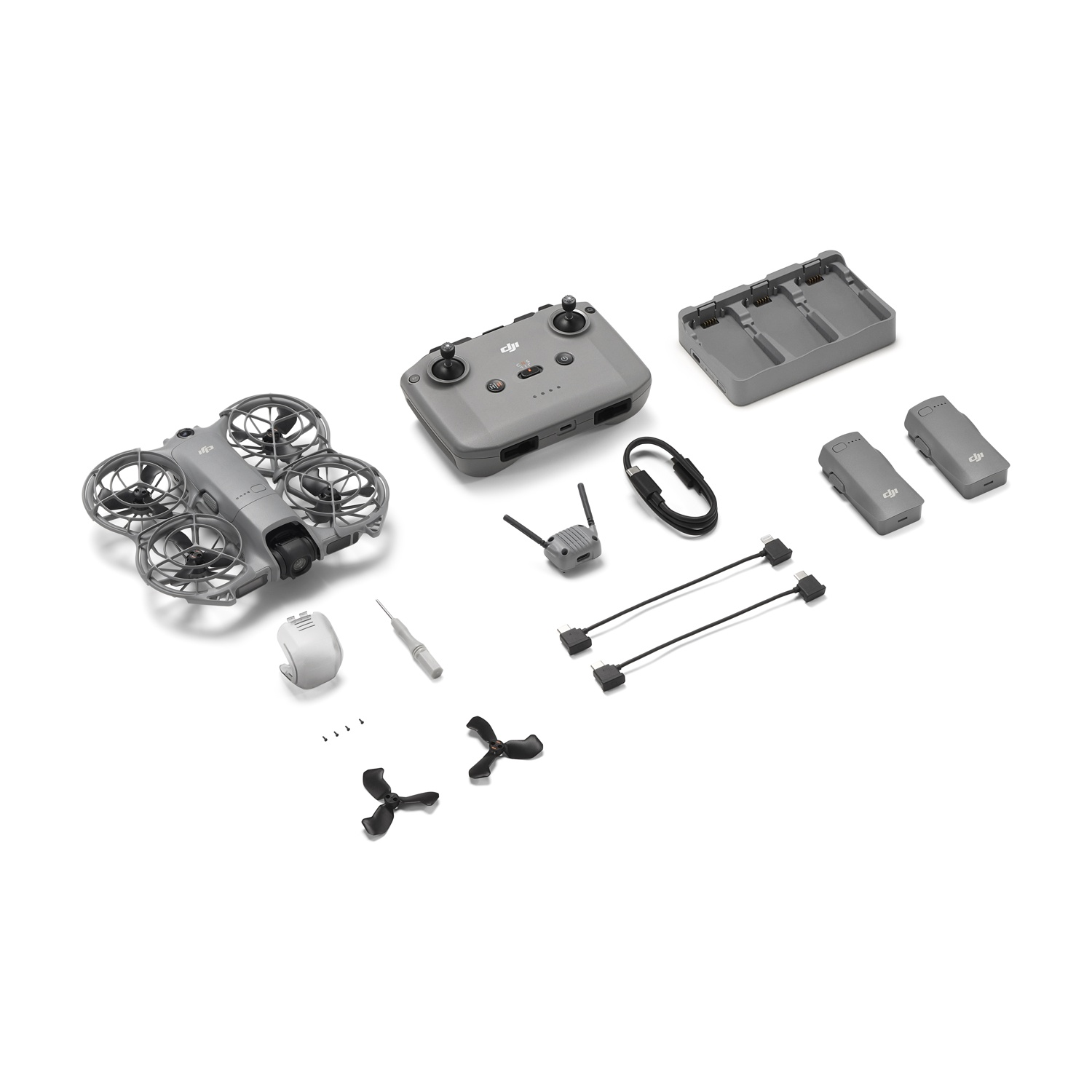 Drone e accessori su sfondo bianco. Include drone, telecomando, caricabatterie, batterie, cavi, antenne ed eliche.