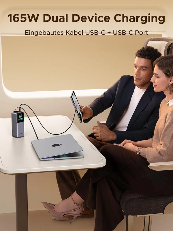 Ein Paar sitzt im Zug und benutzt einen Laptop und ein Tablet, die mit einem 165-W-Dual-Gerät aufgeladen werden.