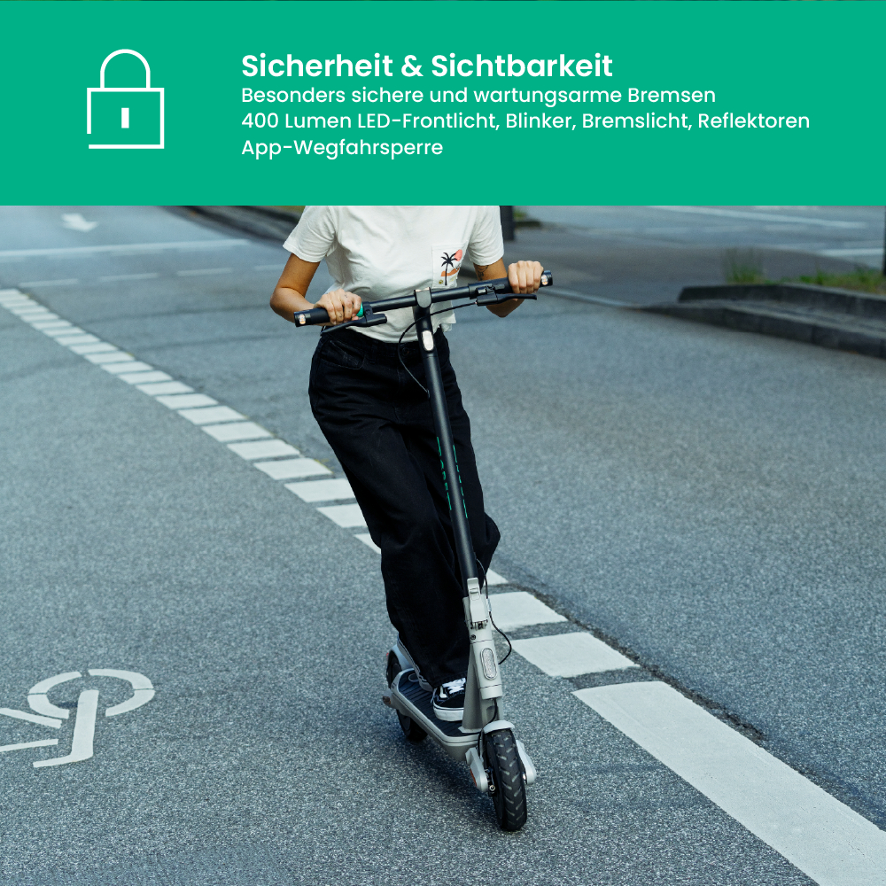 Eine Person fährt mit einem Elektroroller auf einer Straße. Sie trägt ein weißes Hemd und eine schwarze Hose. Der Roller ist grau und schwarz.