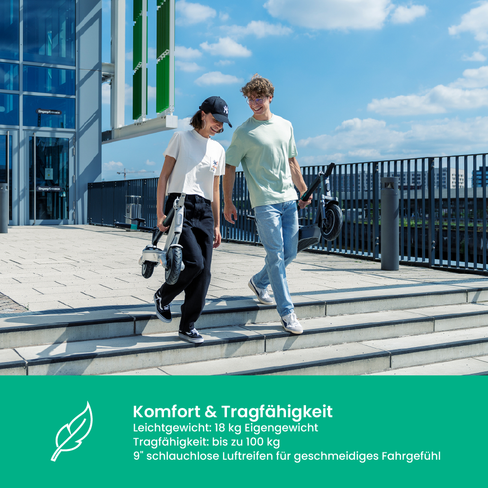 Zwei Personen gehen Treppen hinunter, jede trägt einen Roller. Die Frau hält einen weißen, der Mann einen schwarzen. Sonniger Tag.