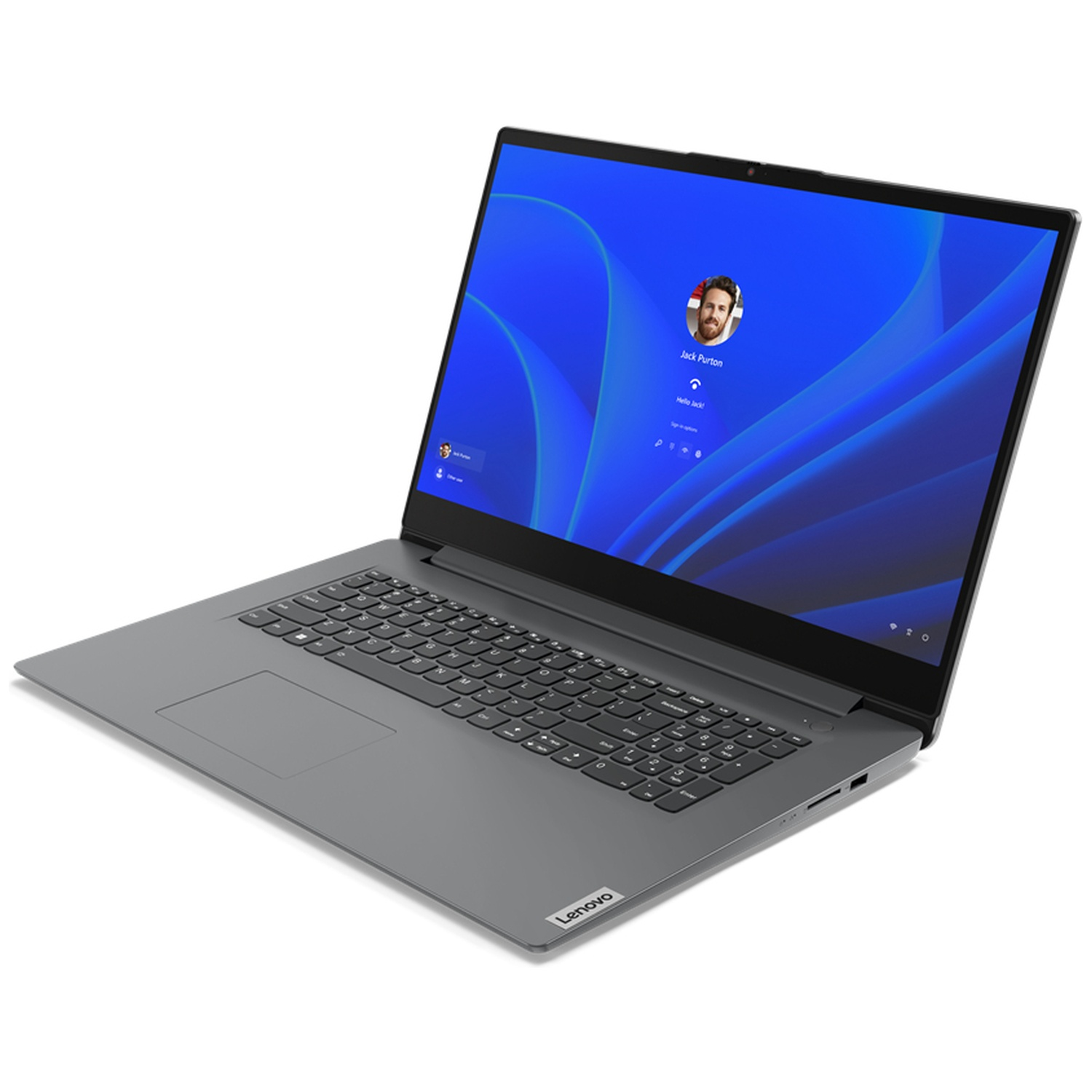 A gray Lenovo laptop is open, displaying a blue Windows login screen. A photo of a man is visible. The keyboard is black.
