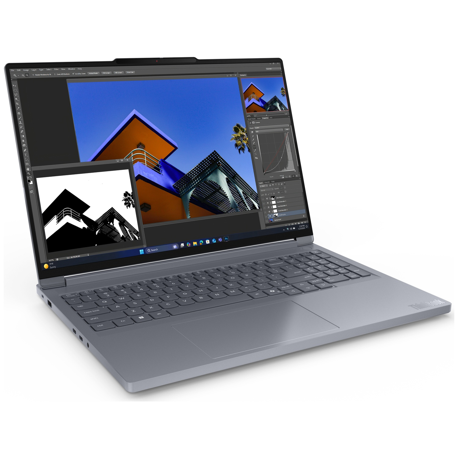 A gray laptop displays an image of colorful buildings on its screen. Keyboard is visible. The laptop is on a white surface.