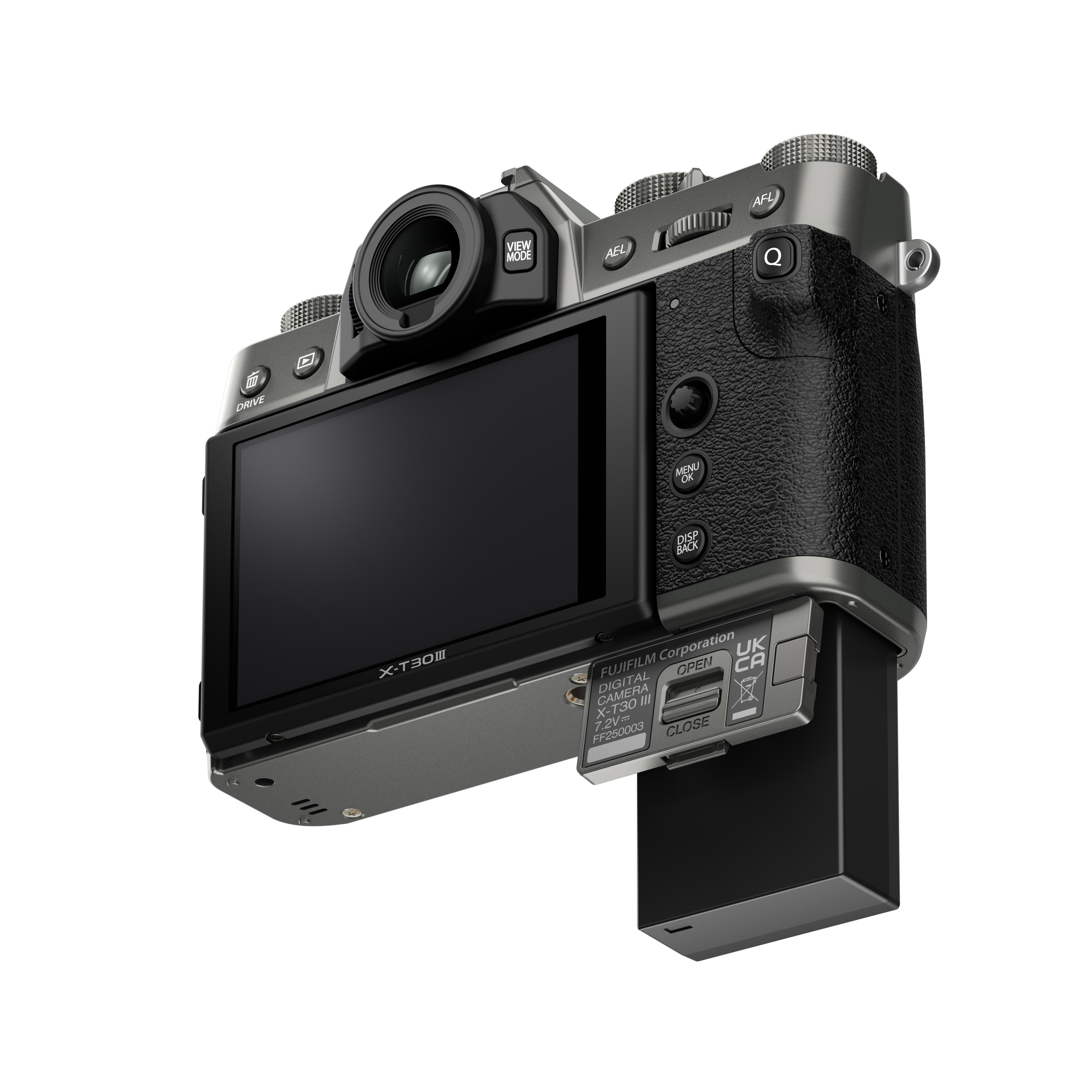 Silberne und schwarze Fujifilm X-T30 III Kamera. Display sichtbar. Batteriefach ist geöffnet.