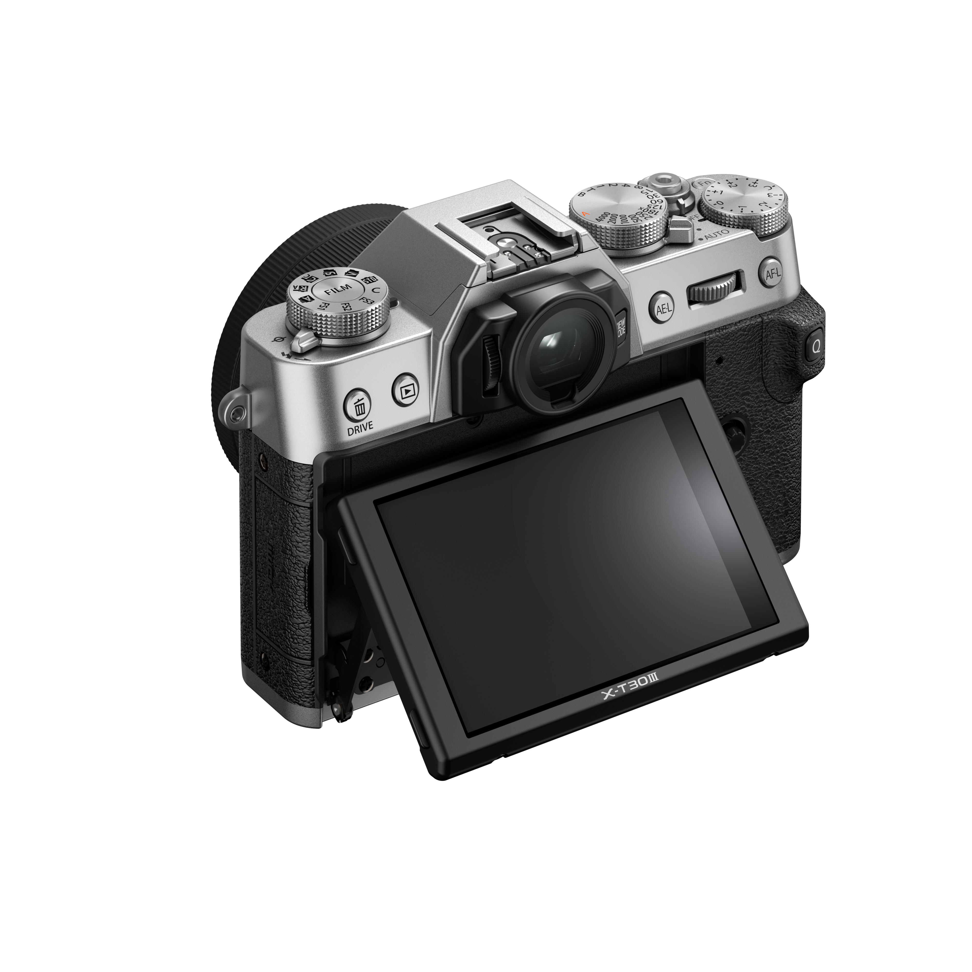 Silberne und schwarze Kamera mit Objektiv und aufklappbarem Bildschirm. Bedienelemente sichtbar. Weißer Hintergrund.