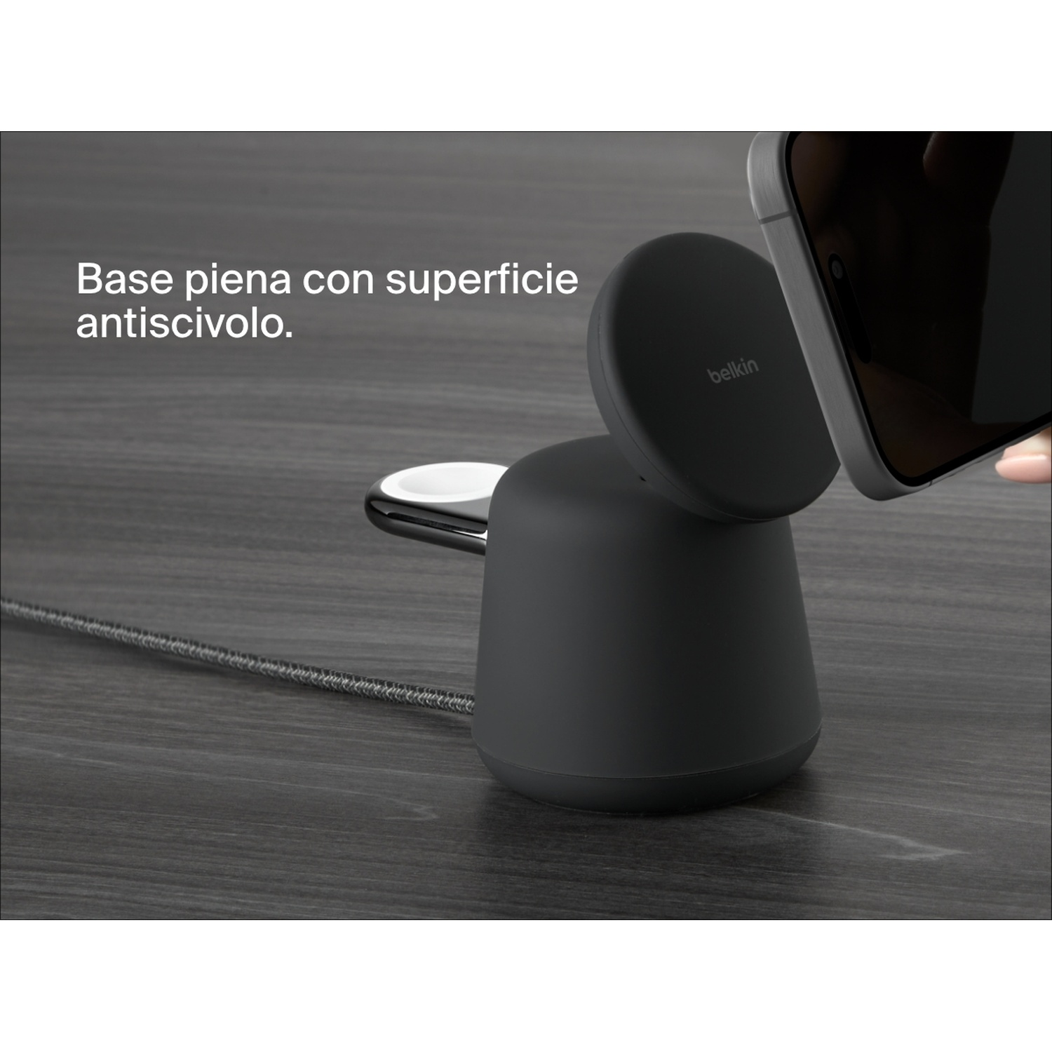 Un caricabatterie wireless nero Belkin con un telefono e un orologio su una superficie di legno.