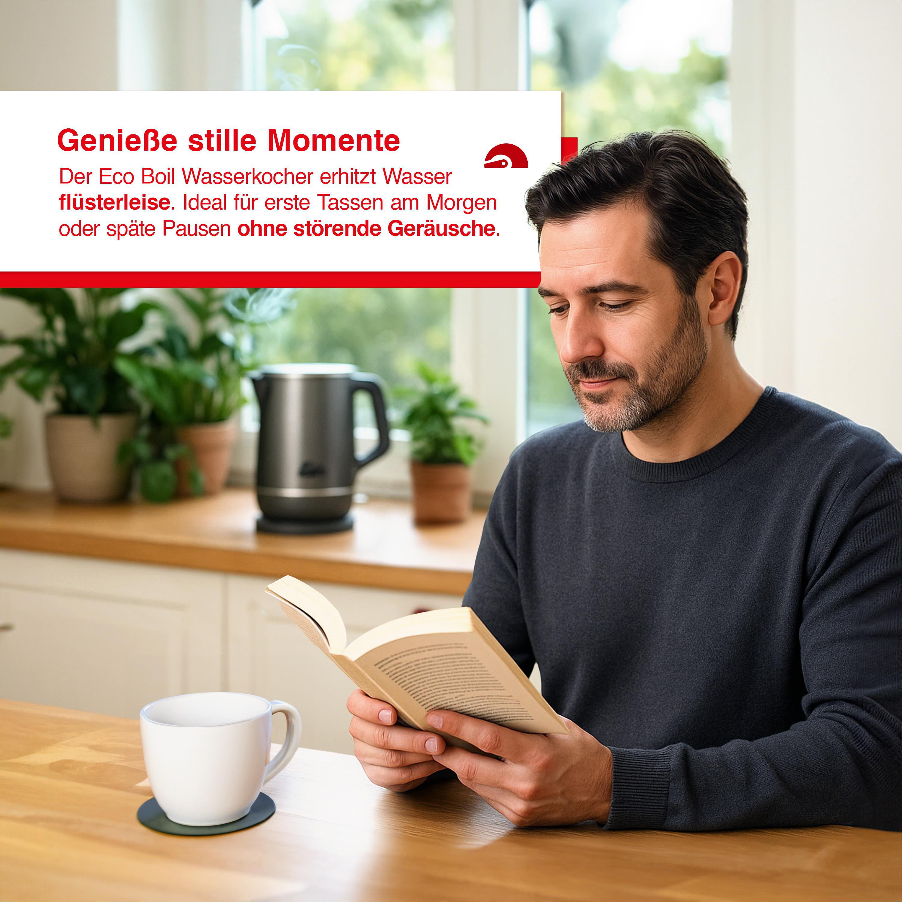 Ein Mann sitzt und liest ein Buch. Eine Kaffeetasse und ein Wasserkocher stehen auf dem Tisch.