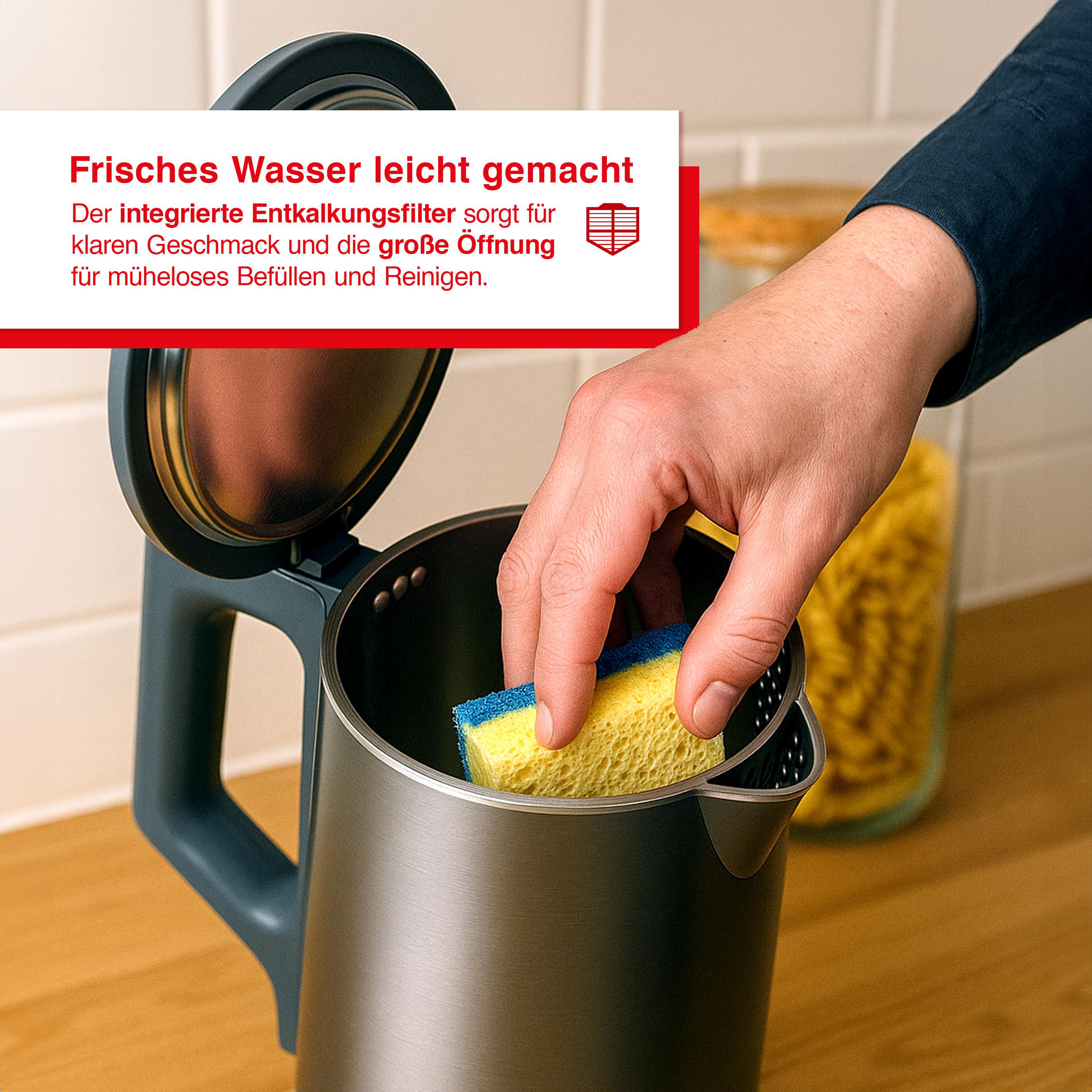 Eine Person reinigt einen Metallkessel mit einem gelb-blauen Schwamm. Im Hintergrund ein Glas mit Nudeln.