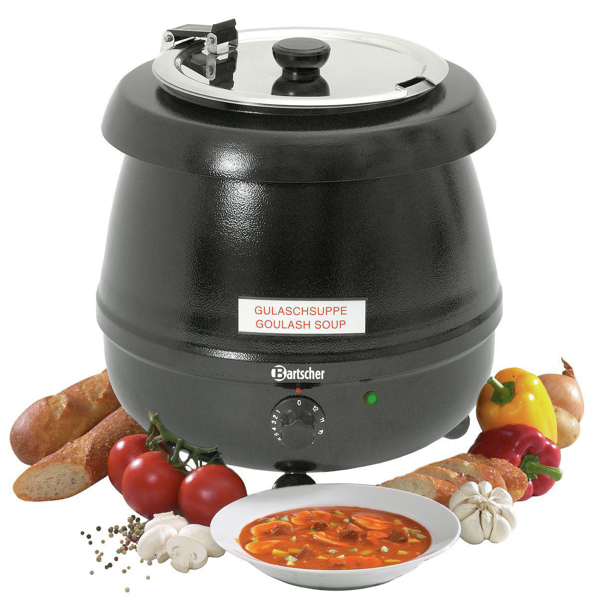 Ein schwarzer Suppentopf mit Deckel, umgeben von Gemüse, Brot und einer Schüssel Suppe.