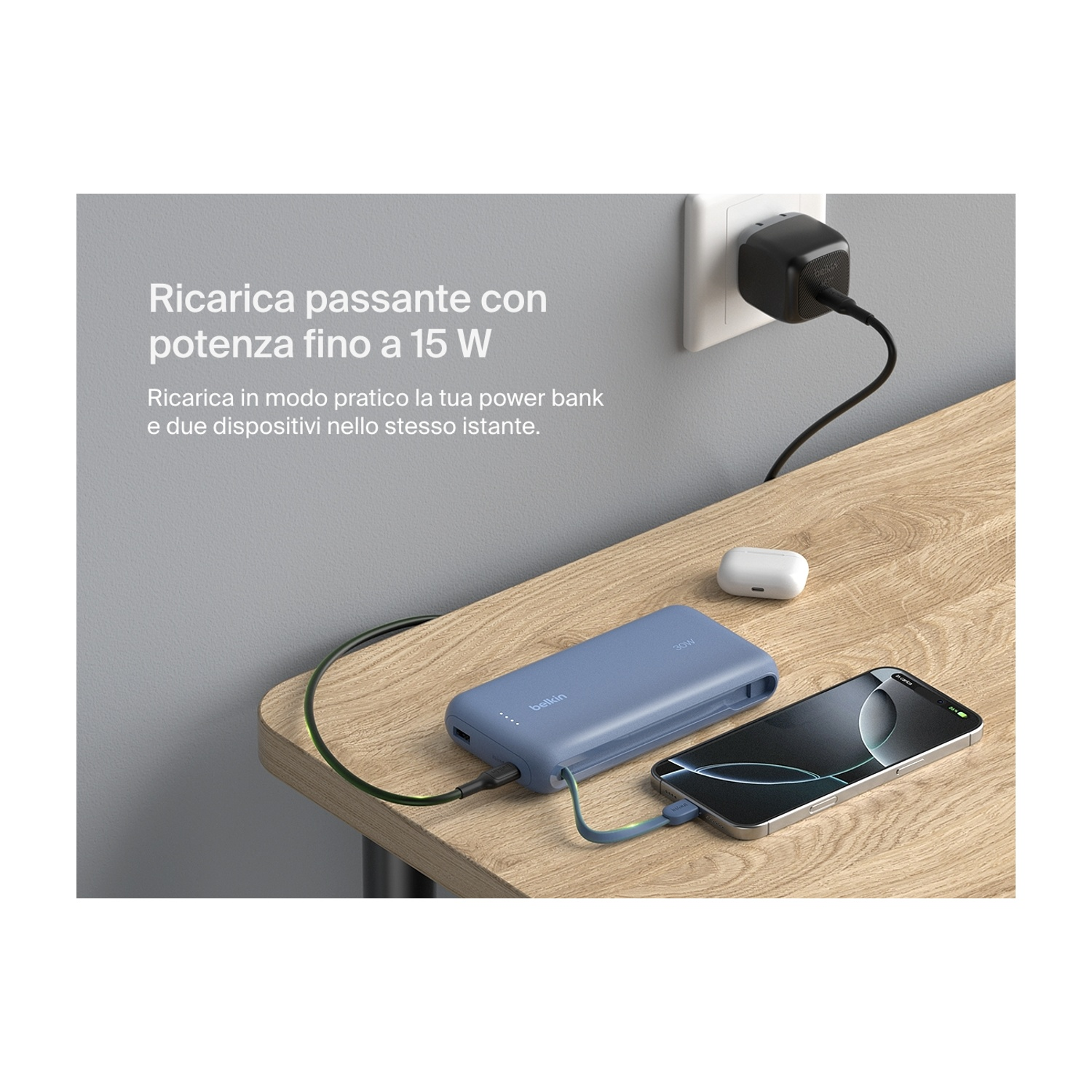 Un telefono e un power bank in carica su un tavolo di legno. Una presa a muro è sullo sfondo. Anche gli AirPods sono sul tavolo.
