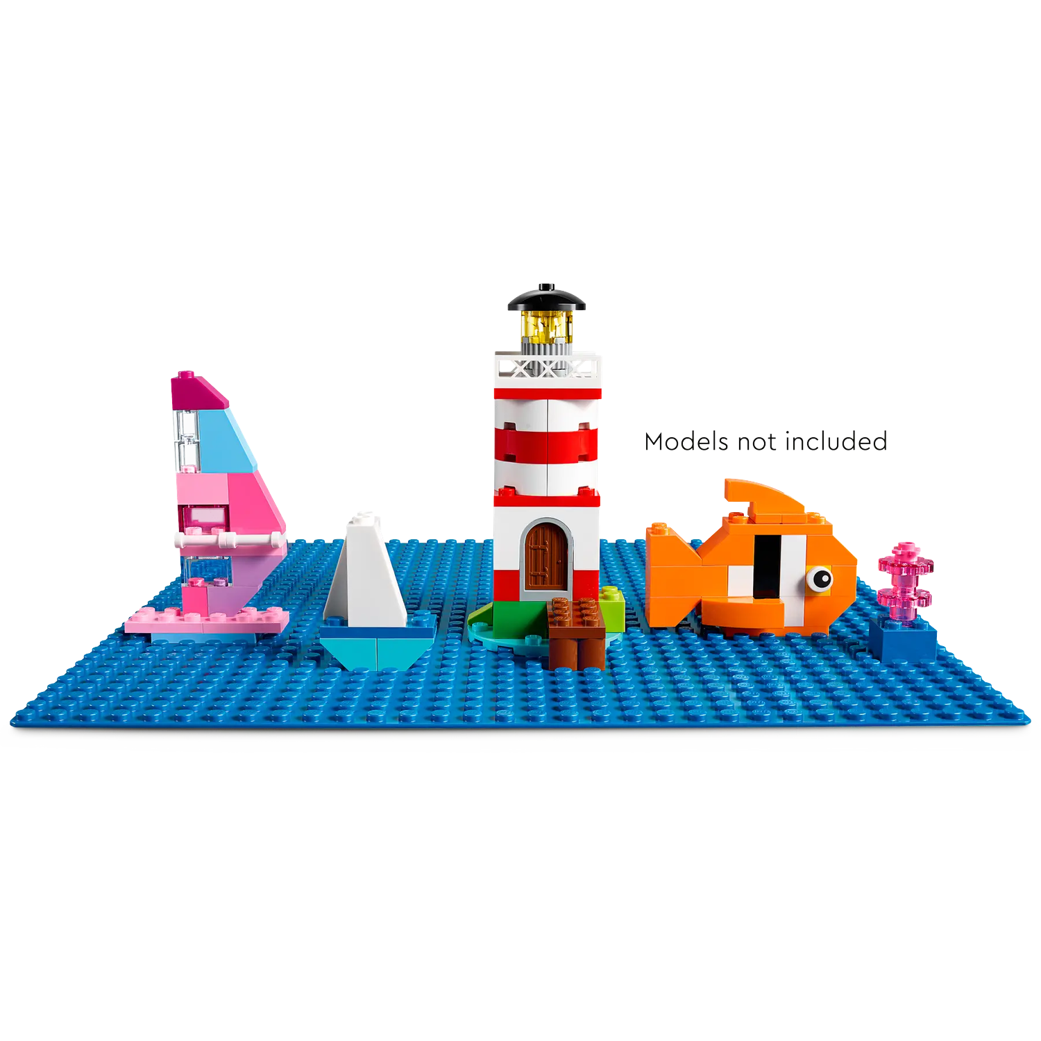 Lego scene on blue baseplate. Includes a lighthouse, sailboat, fish, and other decorative elements.