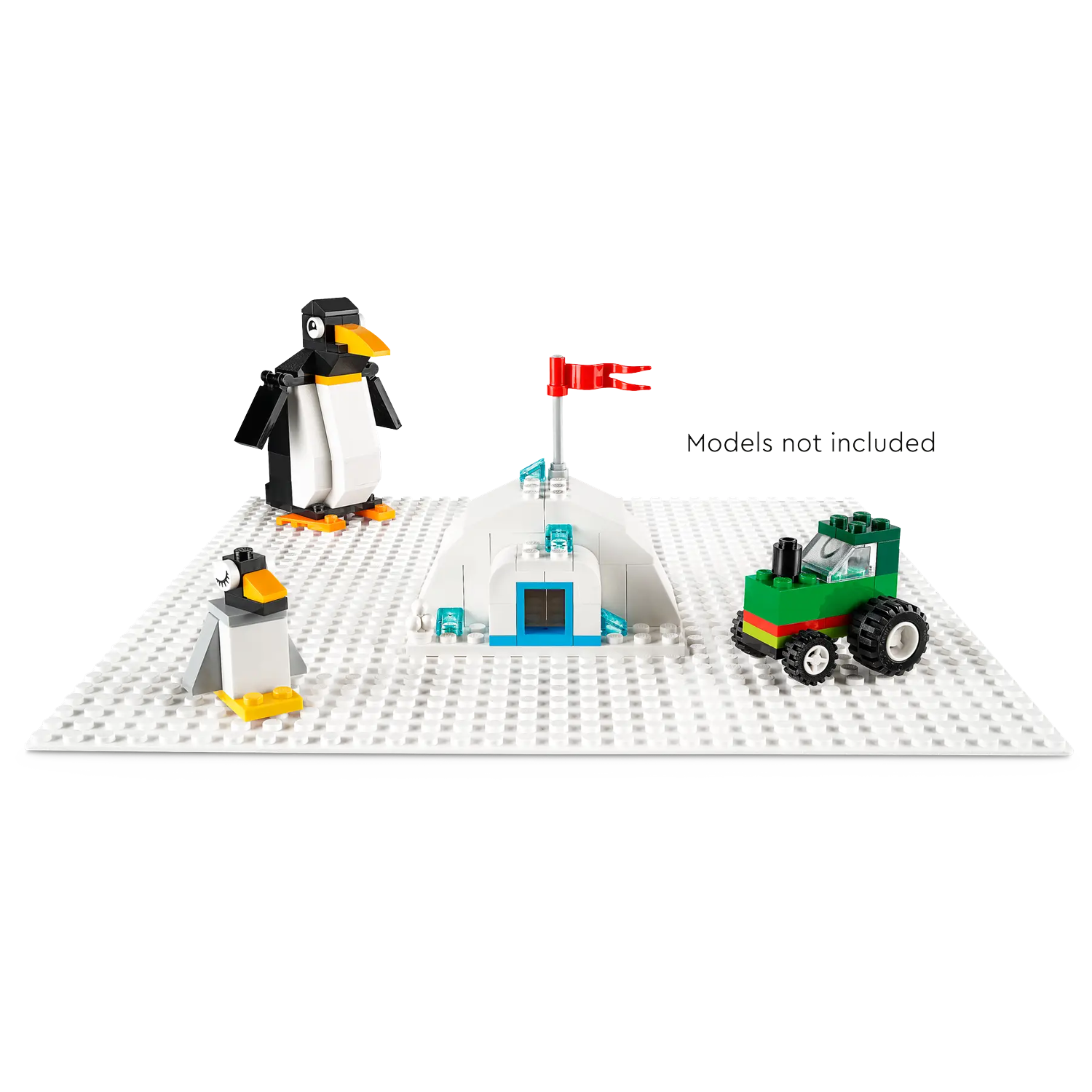 Een Lego-scène met pinguïns, een iglo en een groene tractor op een witte basis. Een rode vlag staat op de iglo.