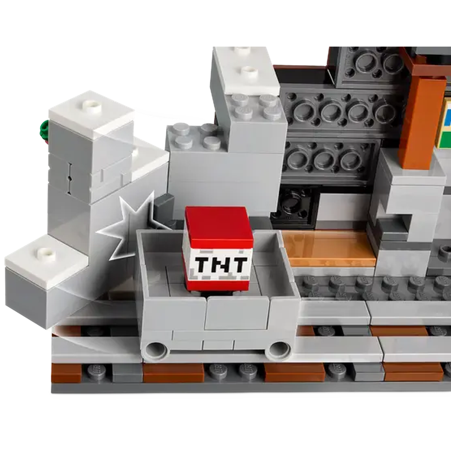 A Lego set featuring a mine cart with a TNT block, grey blocks and tracks. The scene is set with a mountain-like structure.