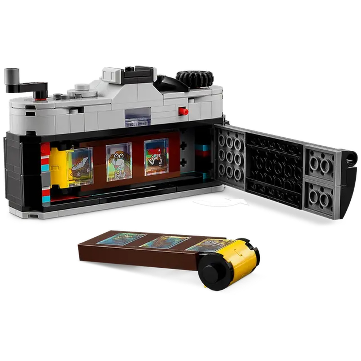 A Lego camera is open, revealing film strips with cartoon images. A film roll and a brown box with images are also present.