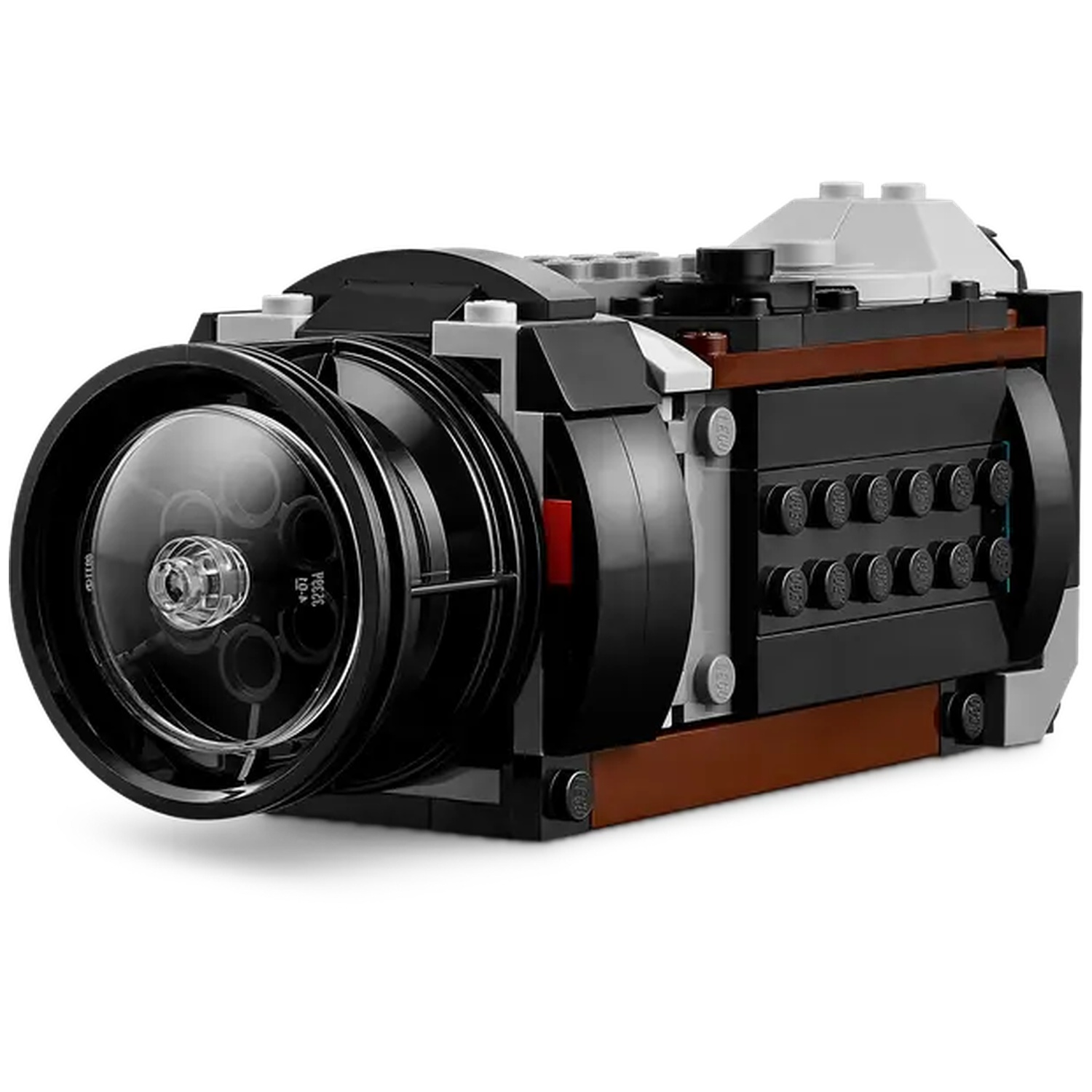 A Lego camera made of black, brown, and gray bricks. The lens is large and clear. It is on a white background.