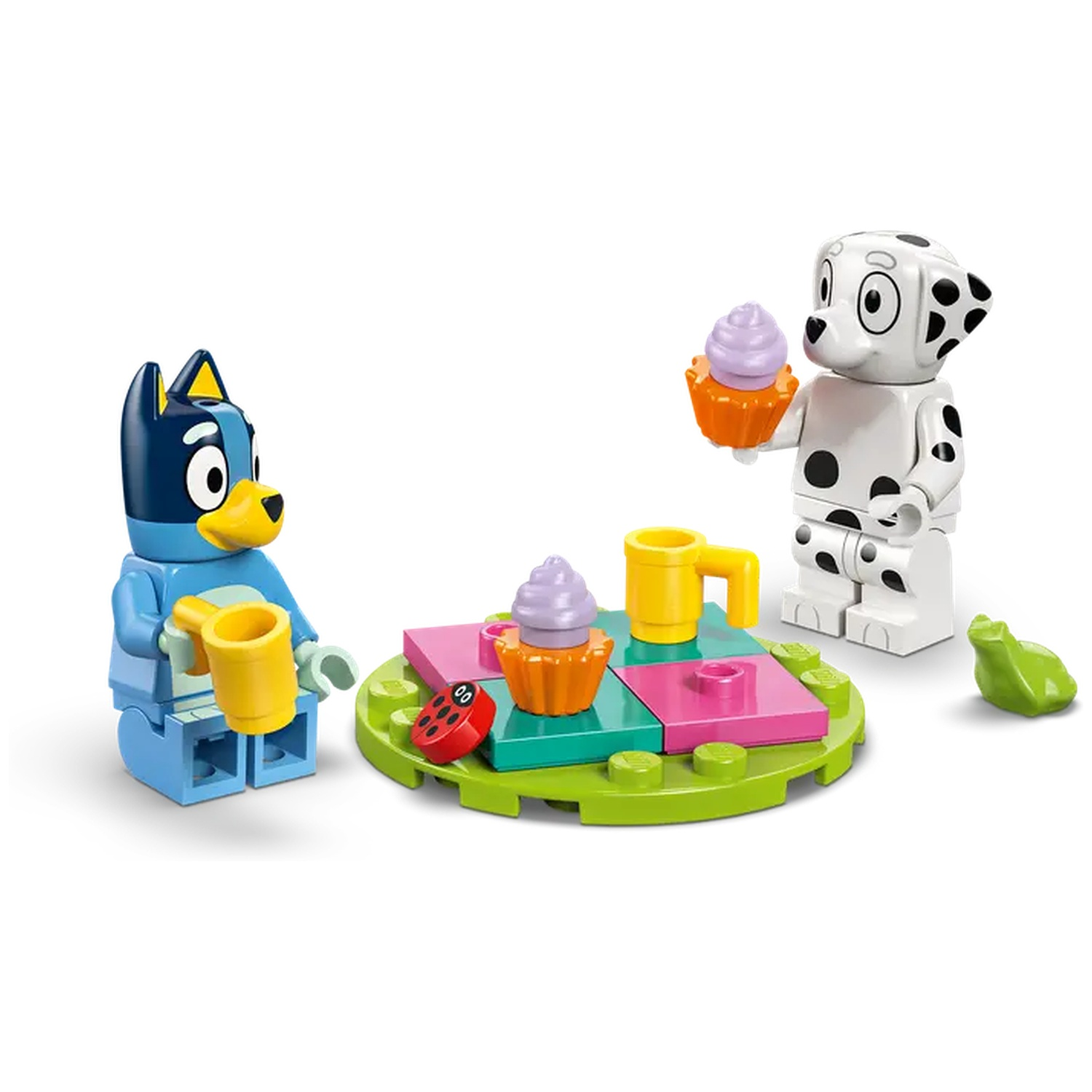 Bluey en een Lego-figuur van een Dalmatische hond met cupcakes en een tafel. Een groene kikker rechts.