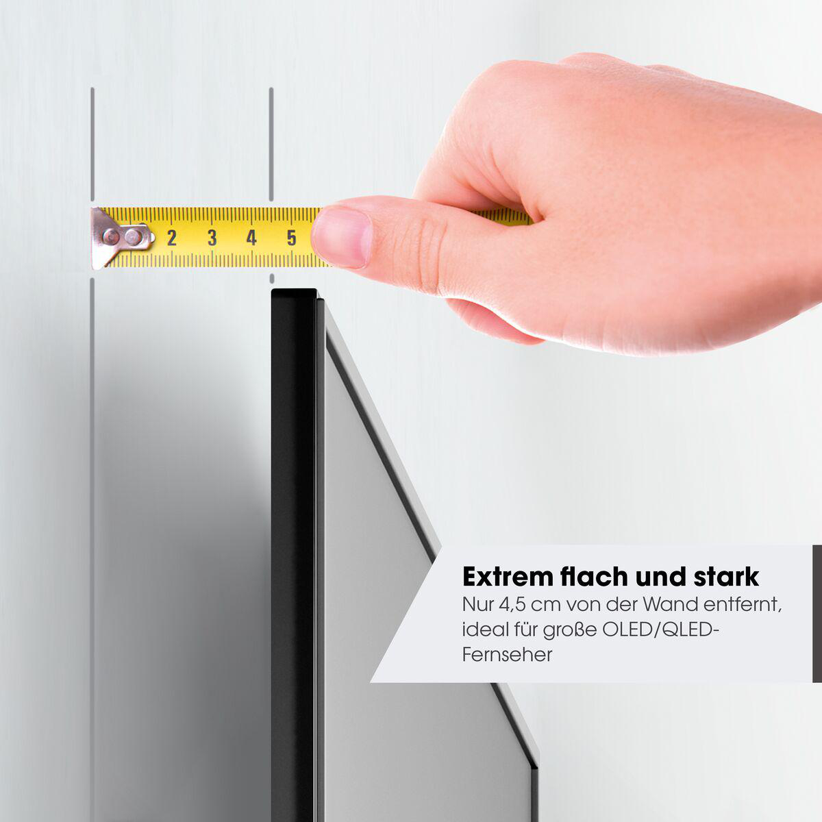 Eine Hand hält ein Maßband bei 4,5 cm von einem schwarzen Bildschirm entfernt. Text: 'Extrem flach und stark' und 'ideal für große OLED/QLED-Fernseher'.