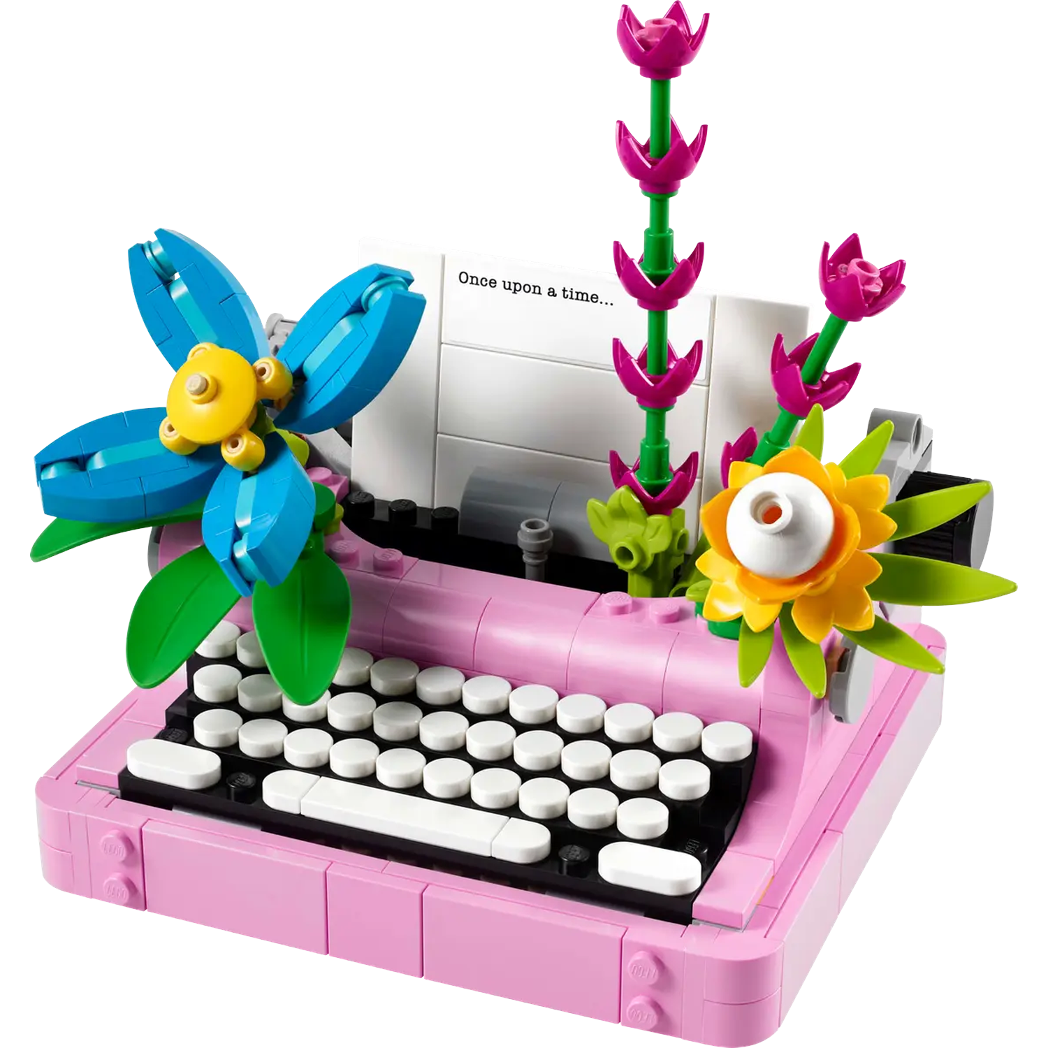 A pink Lego typewriter with flowers. A blue flower on the left, yellow and white flowers on the right, and pink flowers in the back.