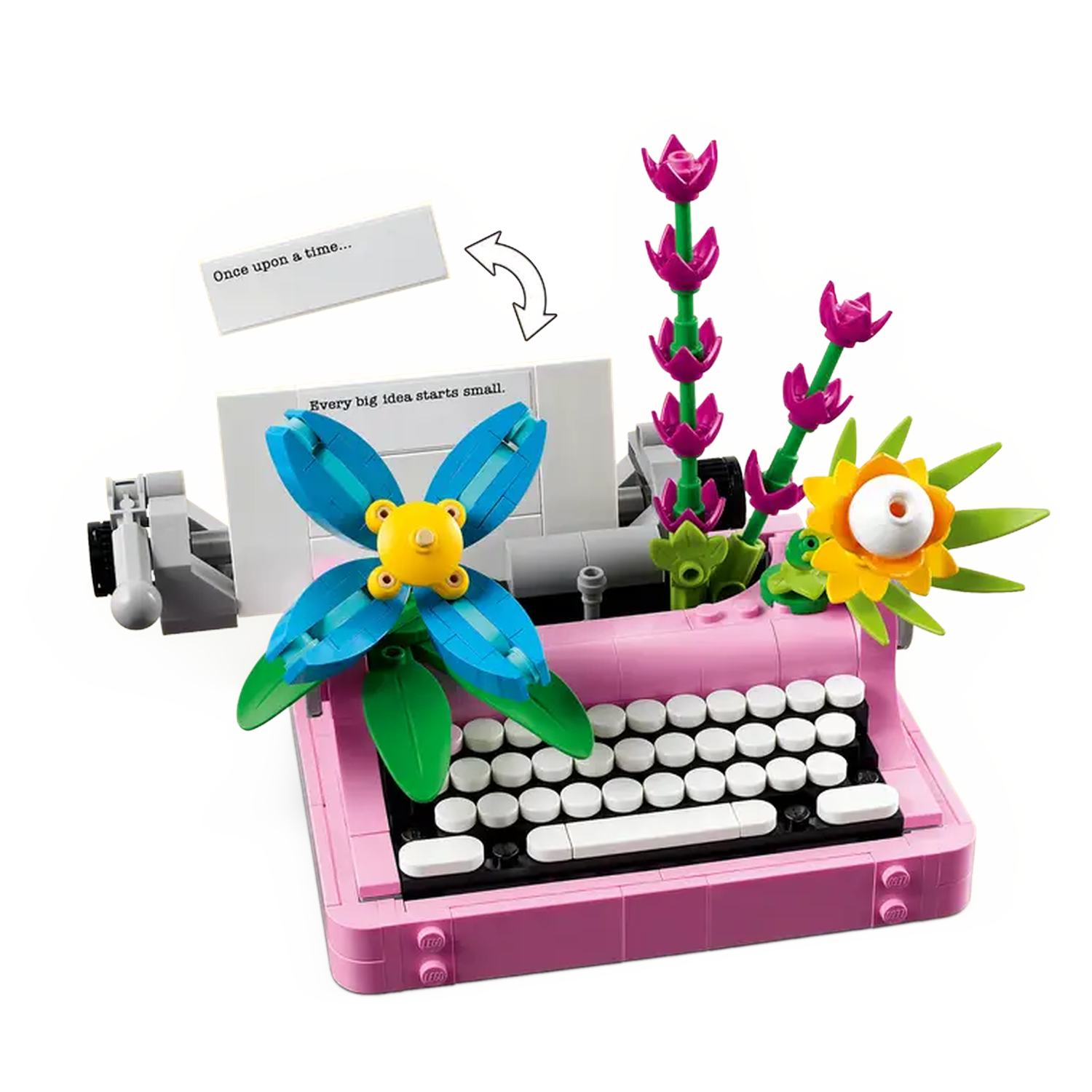 A pink Lego typewriter with white keys and floral decorations. A blue flower and purple flower stalks are on top. A paper reads 'Once upon a time...'