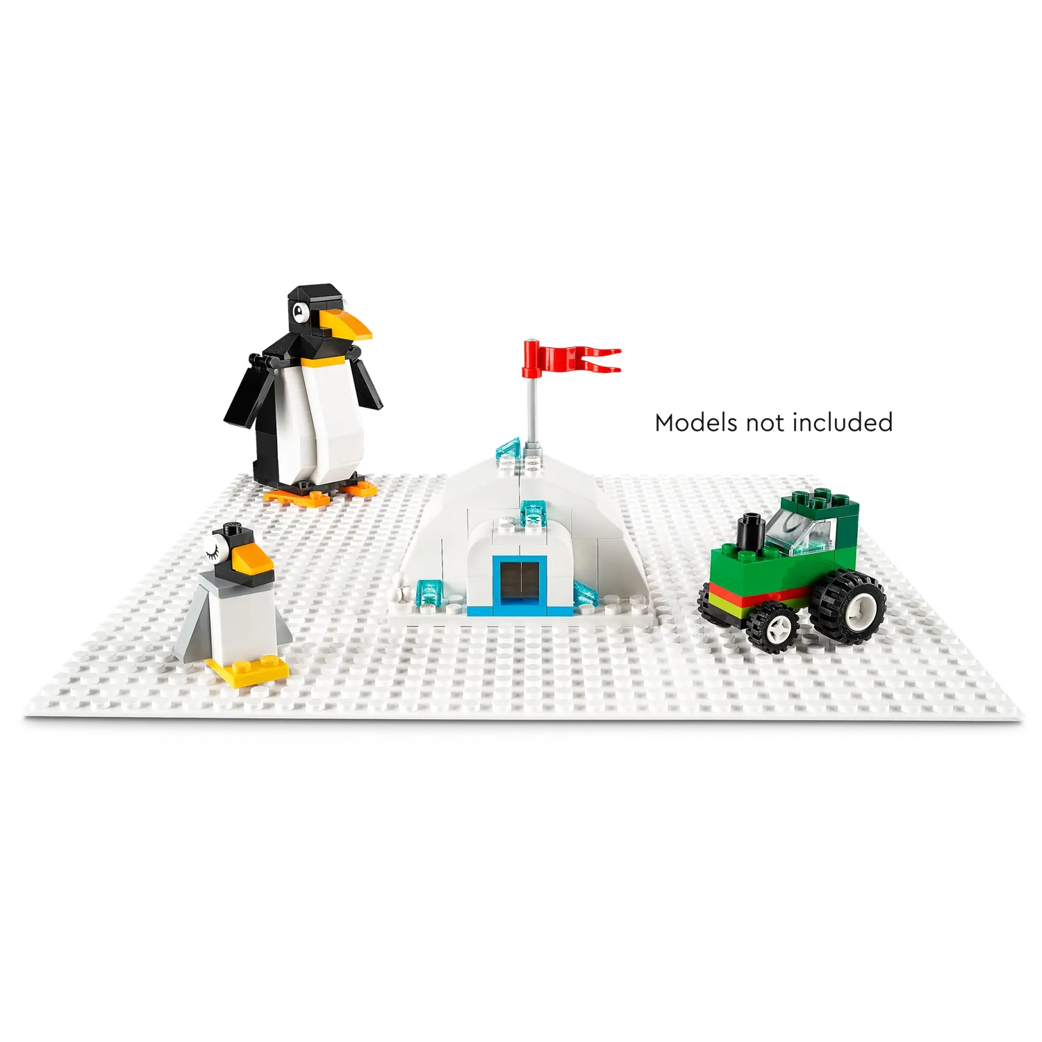 Scène Lego avec pingouins, igloo et tracteur vert sur une base blanche. Drapeau rouge sur l'igloo. Texte : Modèles non inclus.