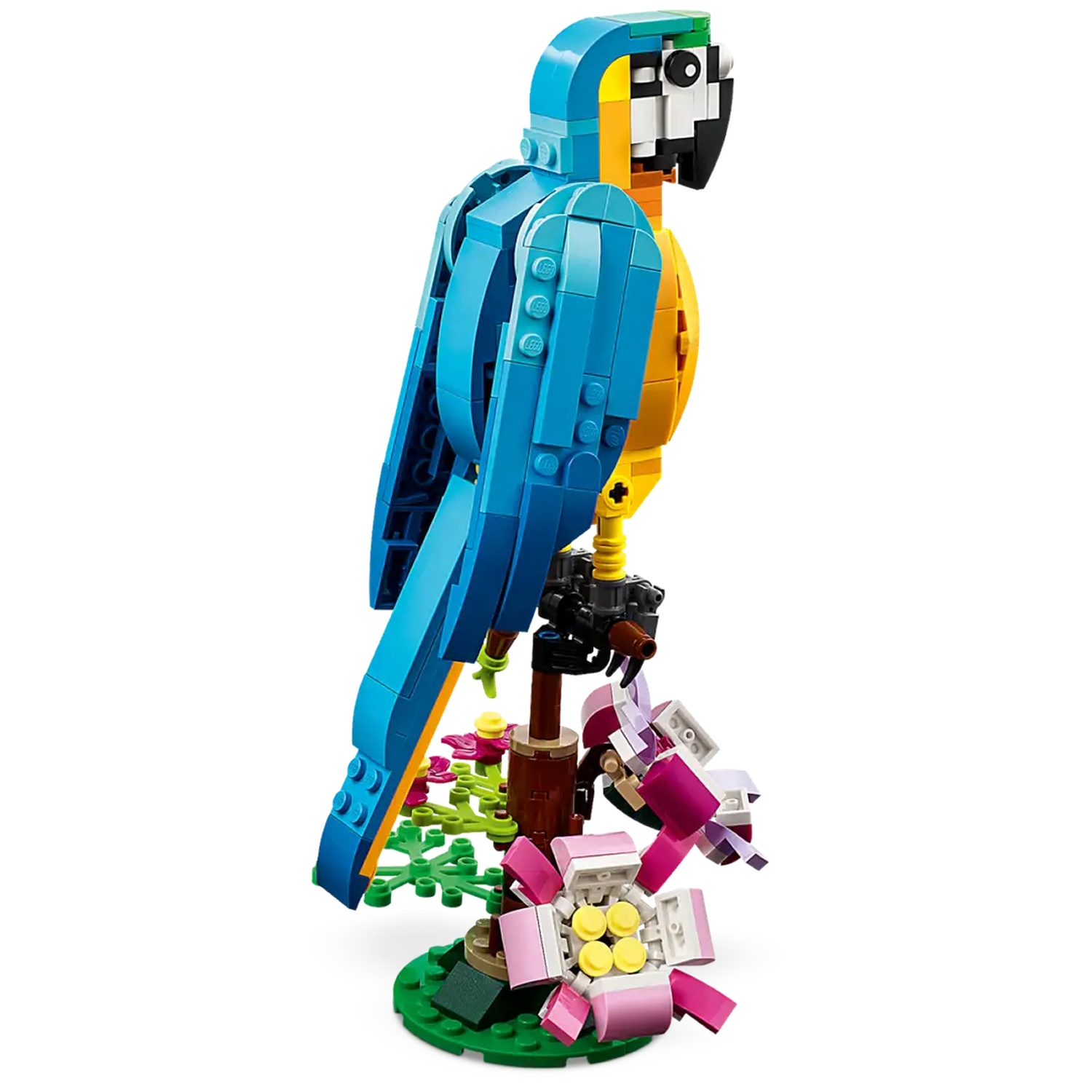 Een Lego papegaaienmodel, voornamelijk blauw en geel, op een bruine tak met bloemen en groene bladeren, tegen een witte achtergrond.